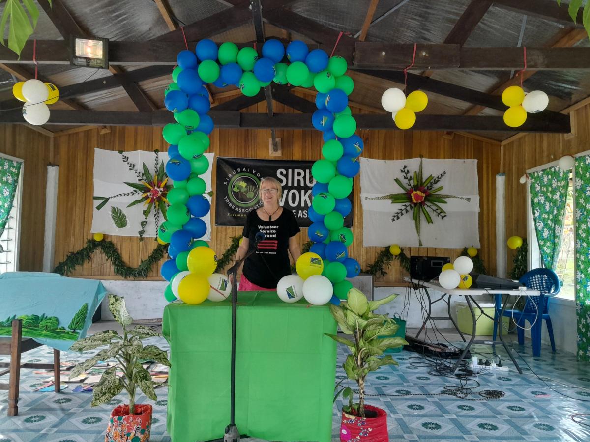 A woman stands at a podium decorated with balloons