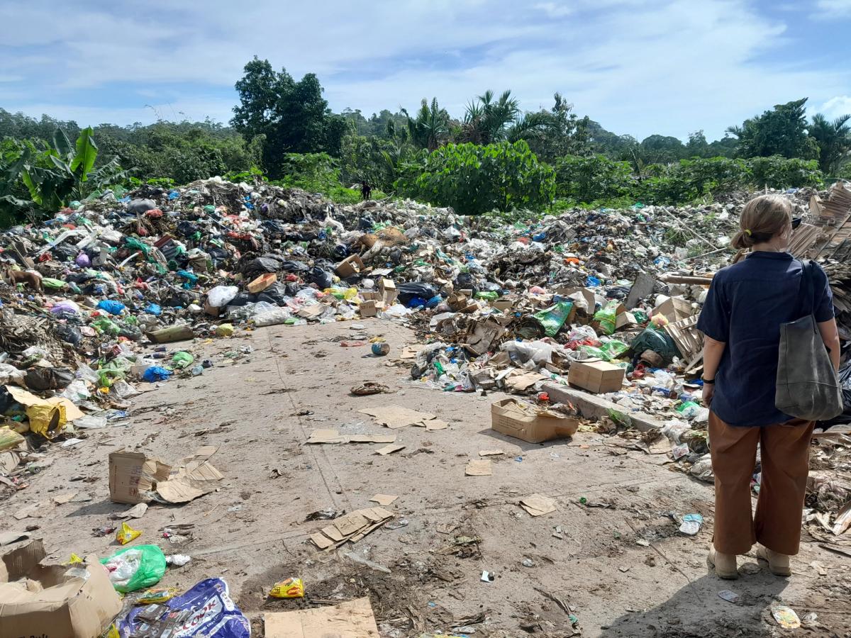 A woman stands and overlooks a pile of rubbish