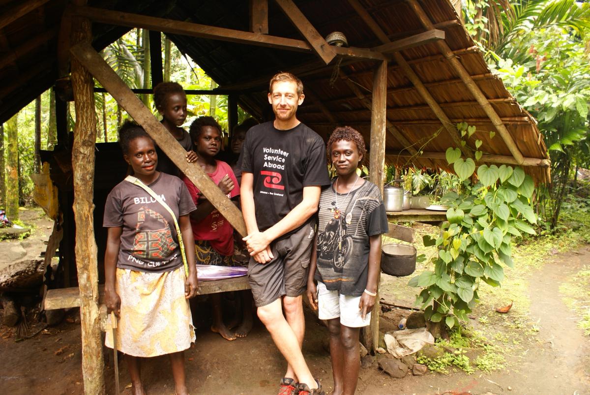 A group of people standing under a shelter and smiling at the camera A group of people standing under a shelter and smiling at the camera