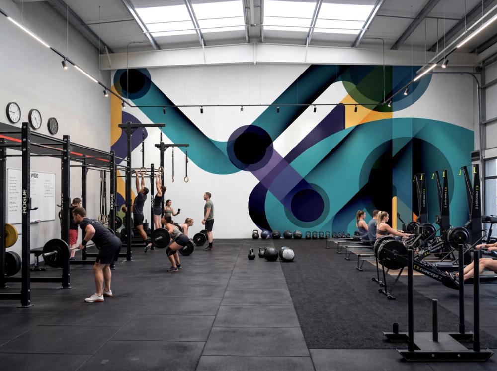 an interior photo of a spacious crossfit gym with an abstract wallpaper mural on the main wall