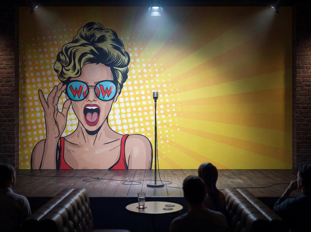 an interior photo of a stage at a comedy club with a cartoon themed wallpaper mural on the wall