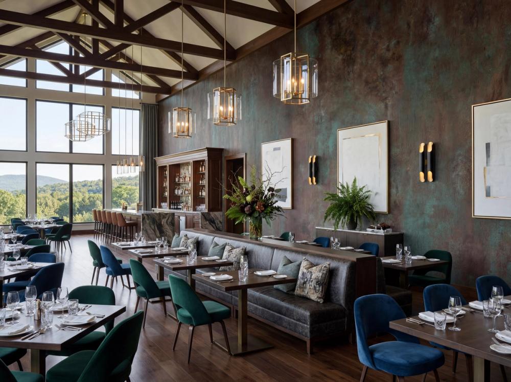 an interior photo of a dining room at a country club house with an abstract mural in brown and green on the wall