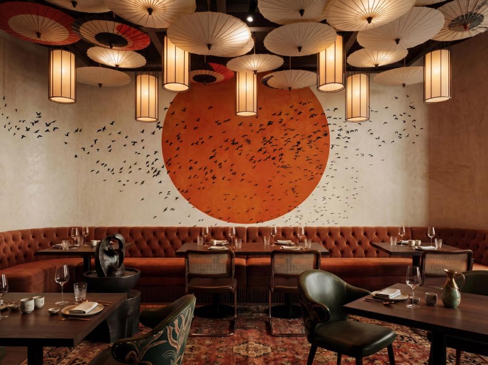 an interior photo of an asian restaurant with a red sun themed wall mural on the wall