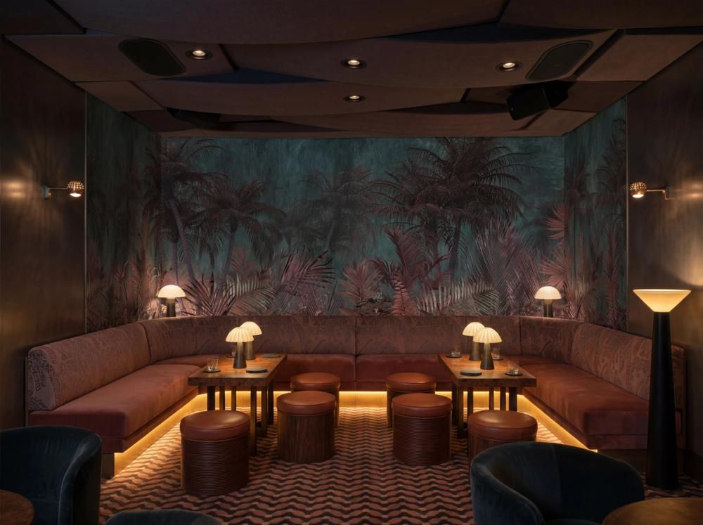 an interior photo of a nightclub with a dark jungle themed wallpaper mural on the wall