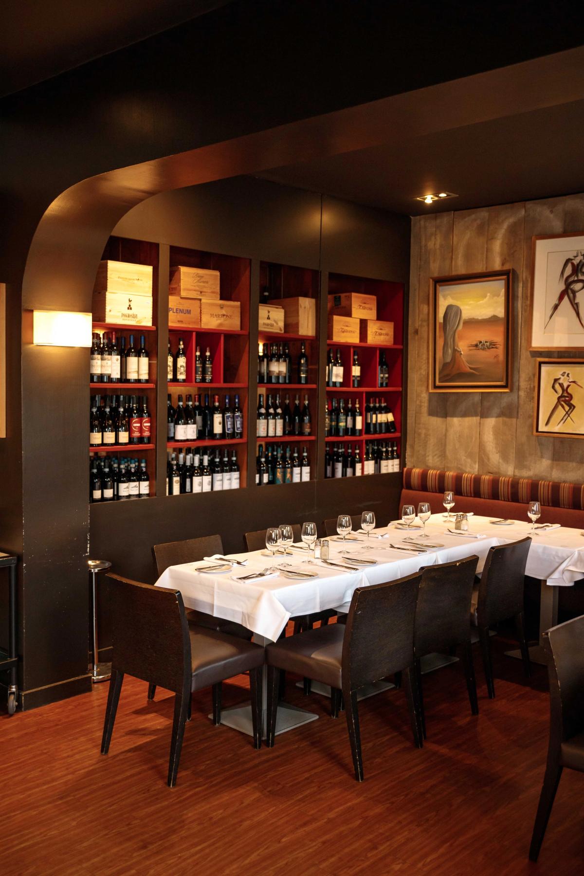 Private dining room featuring elegant table settings, wine display, and artistic decor