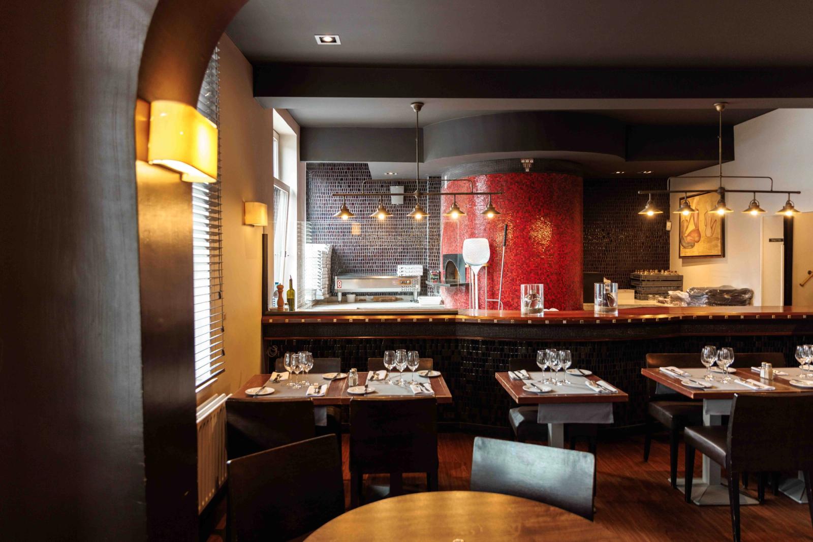 Intérieur du restaurant Il Carpaccio avec tables élégantes et bar à mosaïque rouge