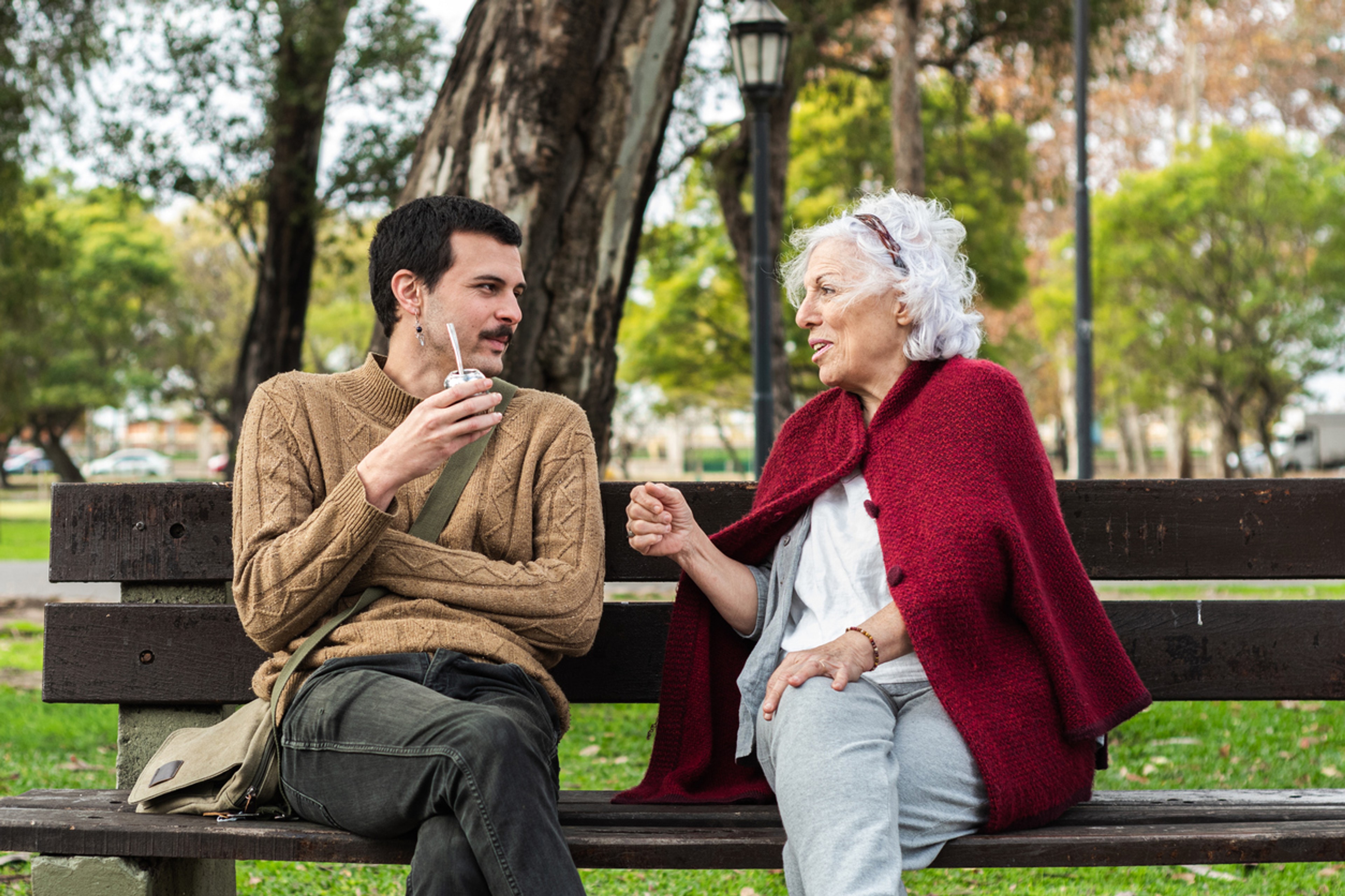 a mother and son talking to each other on a park bench 