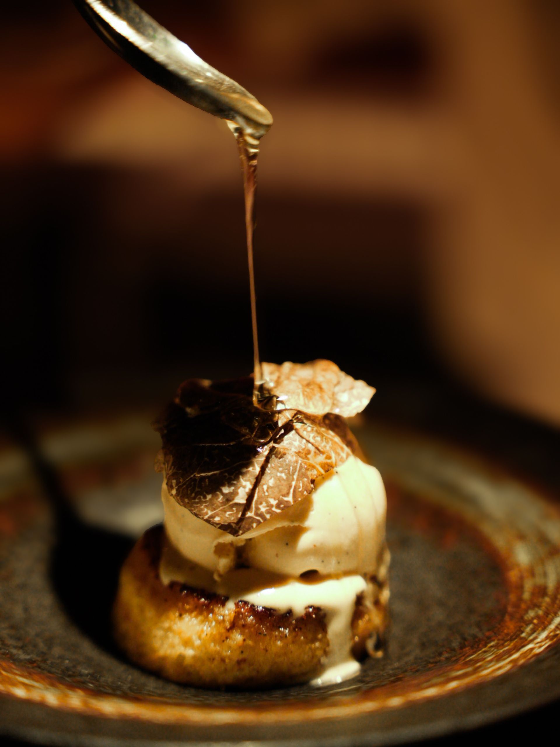 Sauce poured over a foie and scallop plate finished with shaved truffle.