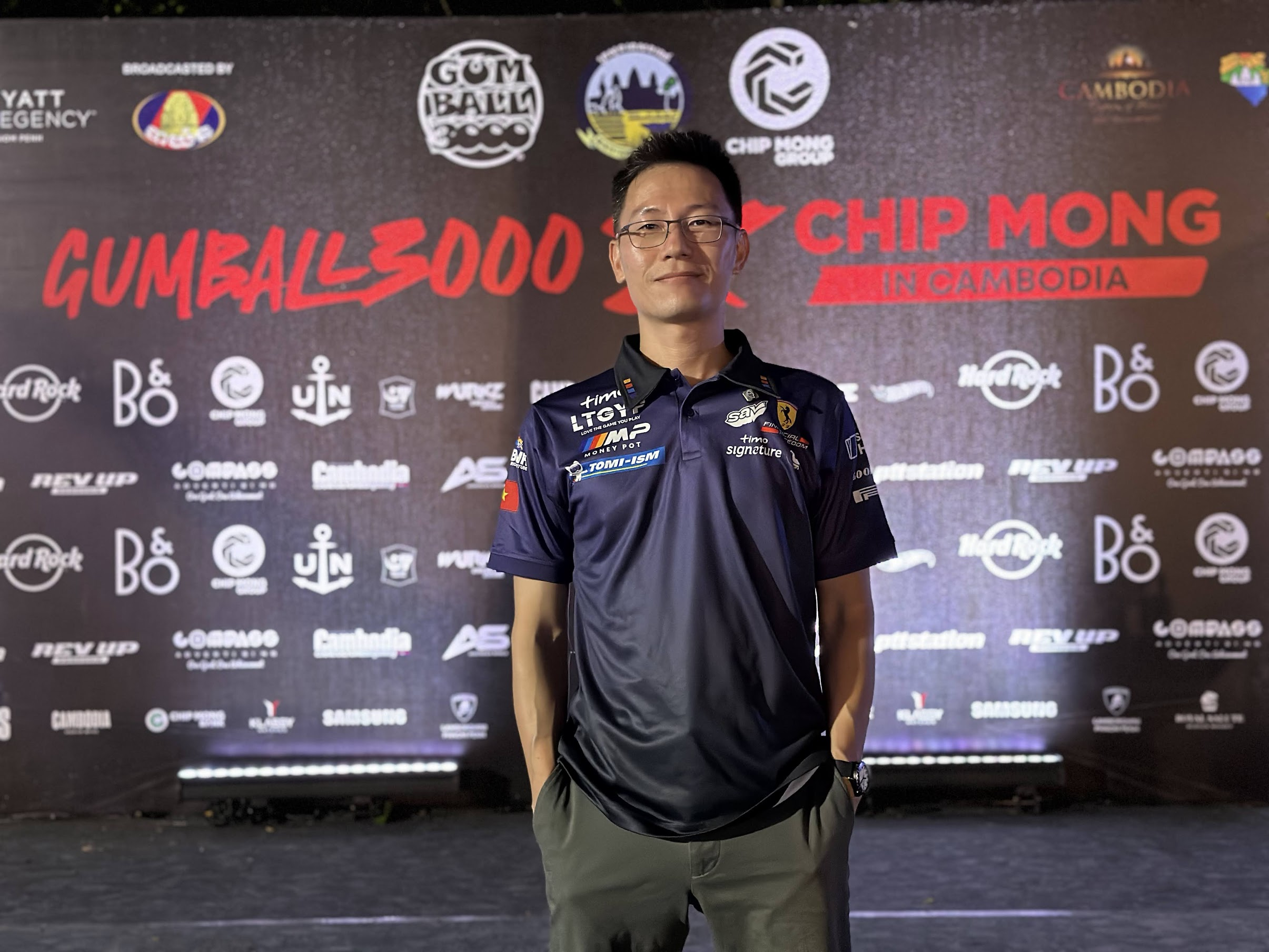 a man stands in front of a sign that says gumbal 3000