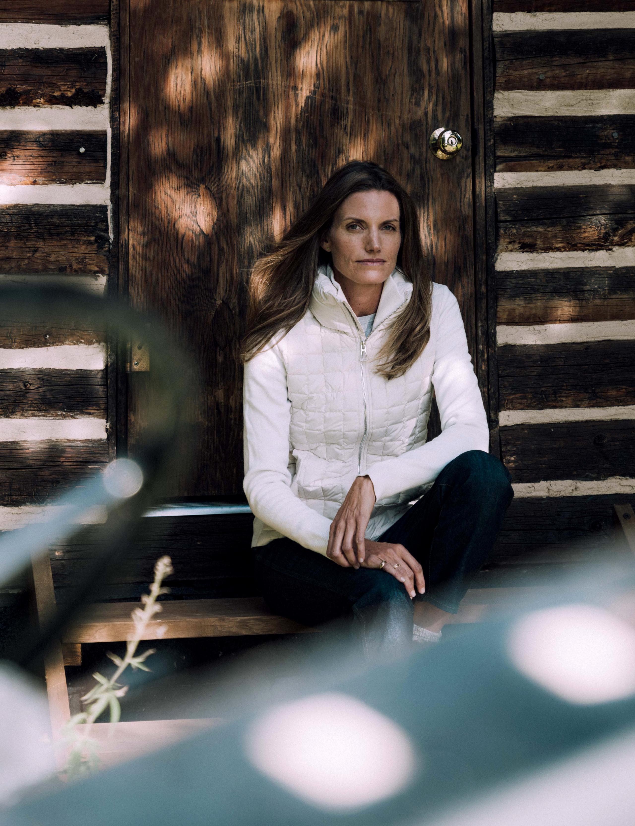 A woman in Phase Full-Zip sitting in front of a cabin.