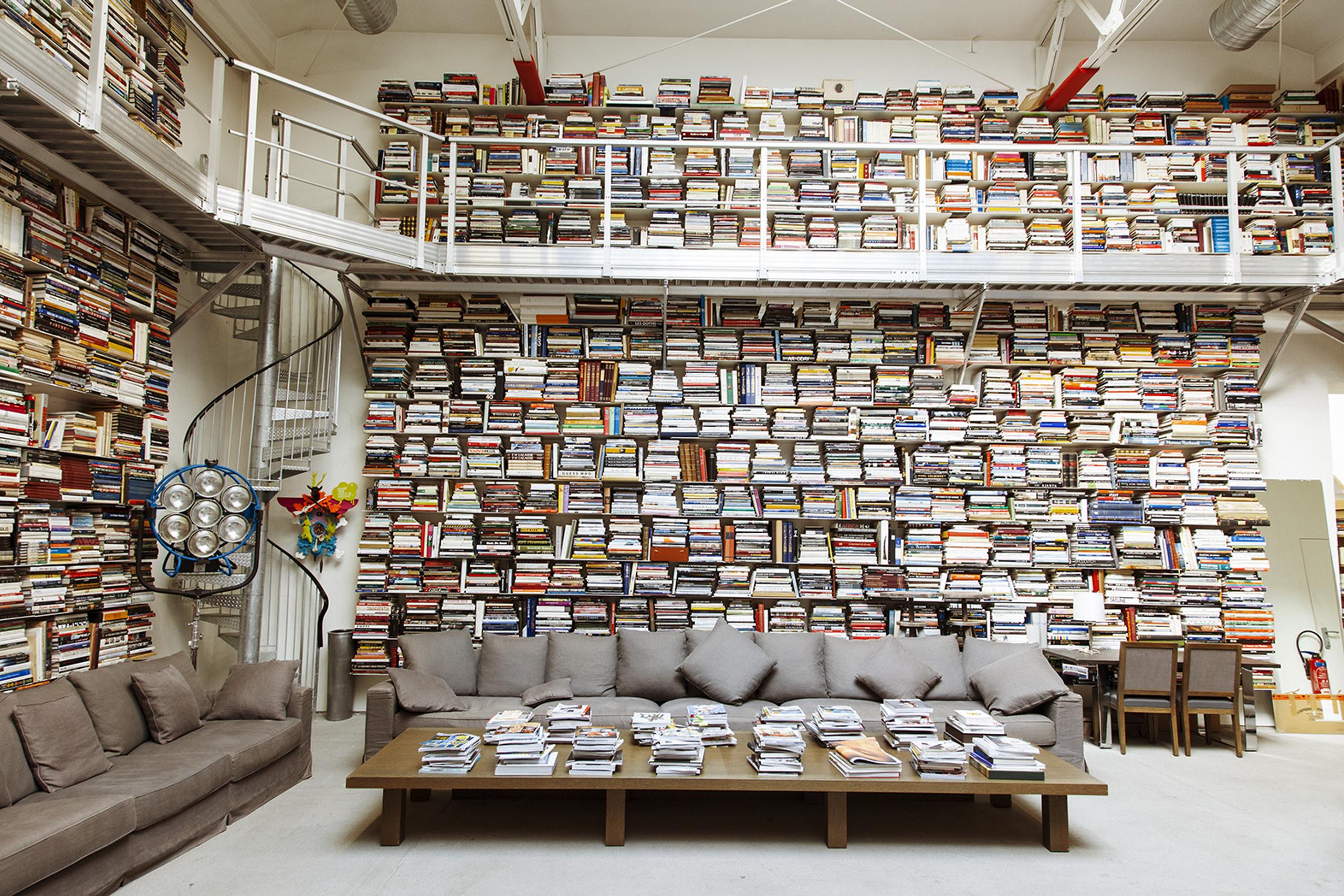 hundreds of books stacked on shelf and on table