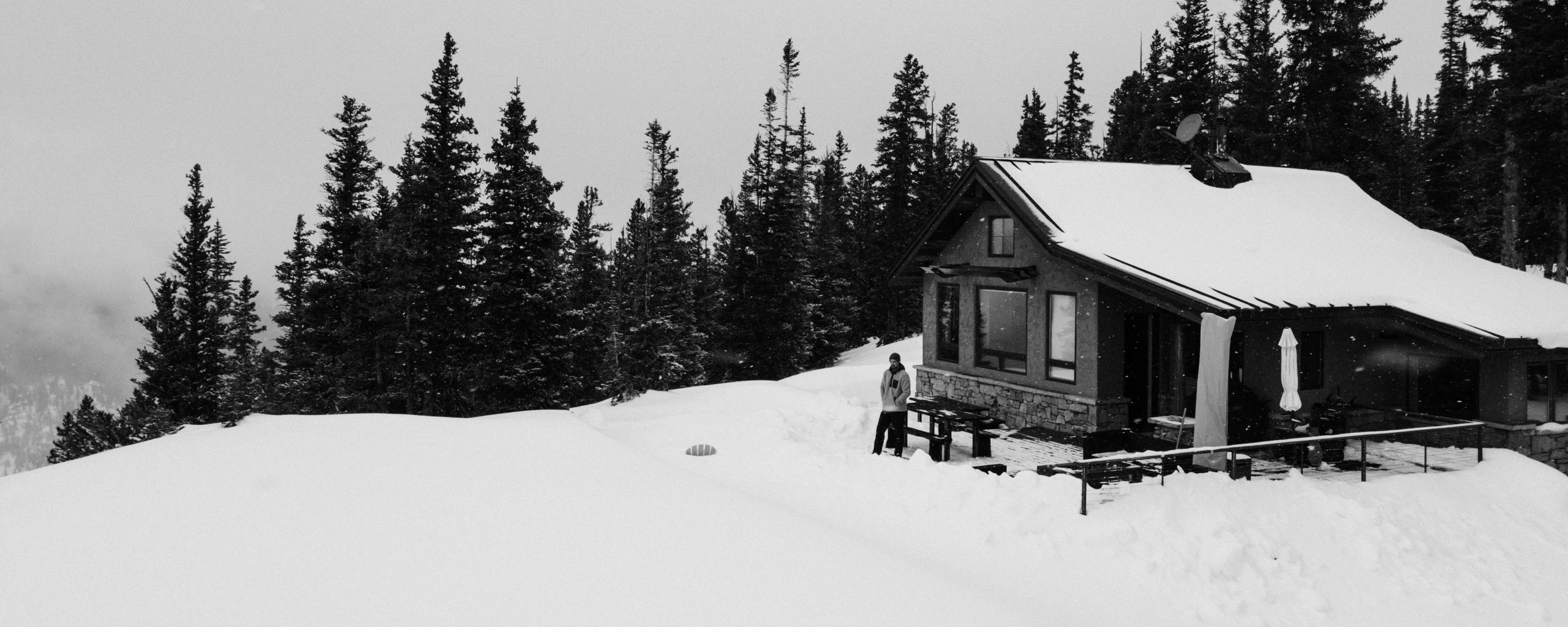Man standing outside cabin in deep winter snow in Aspen, Colorado