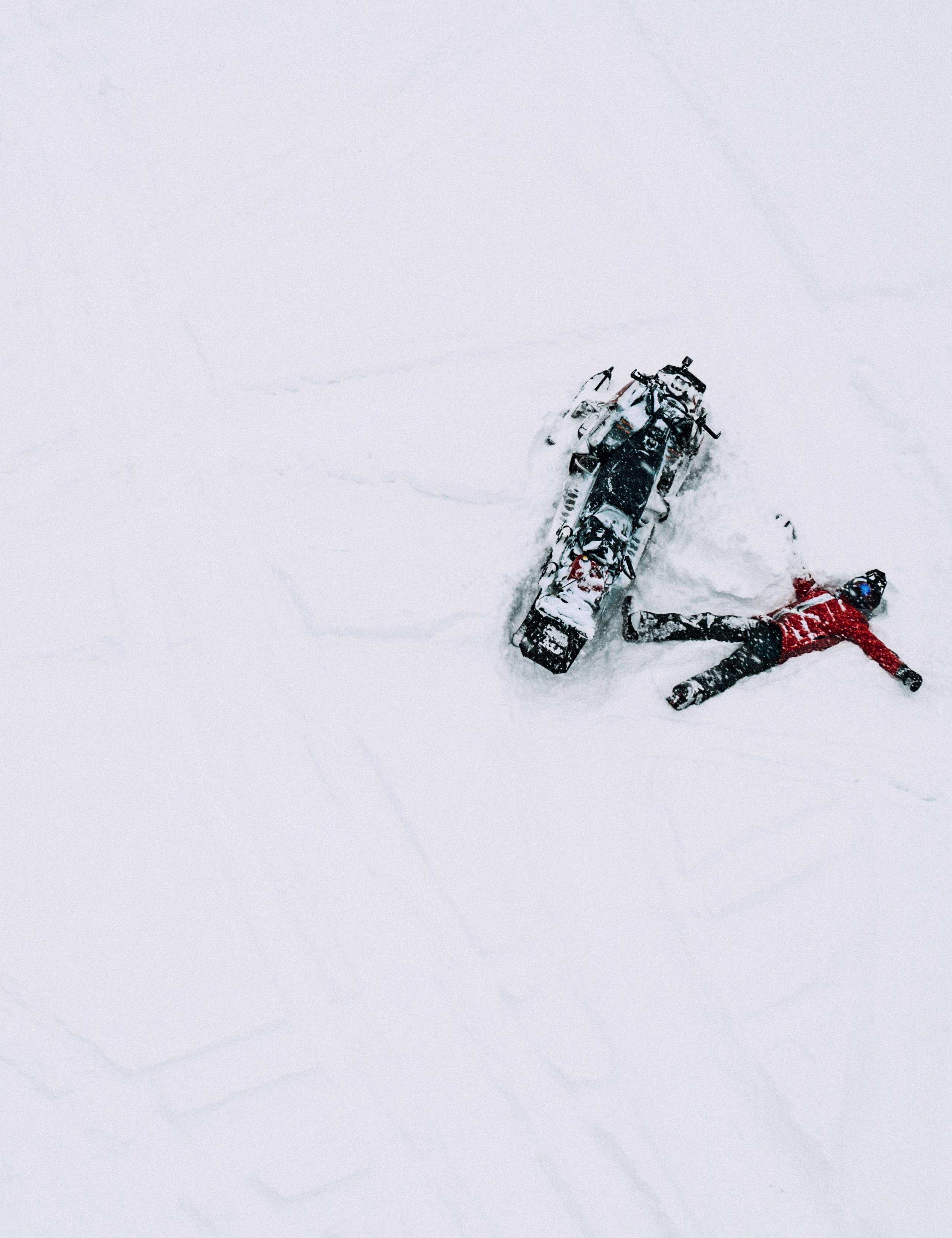Aerial view of man lying next to snowmobile in Aspen