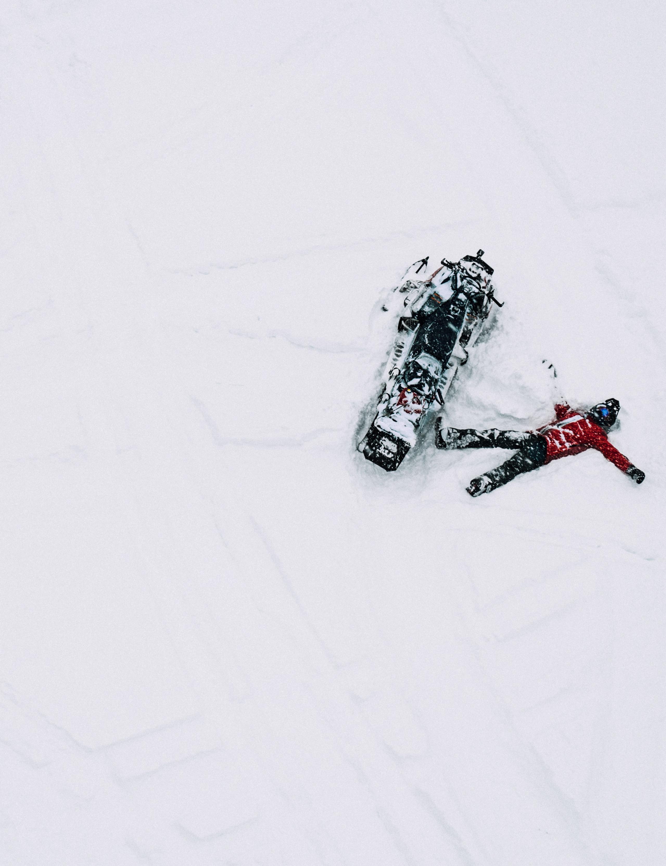 Aerial view of man lying next to snowmobile in Aspen