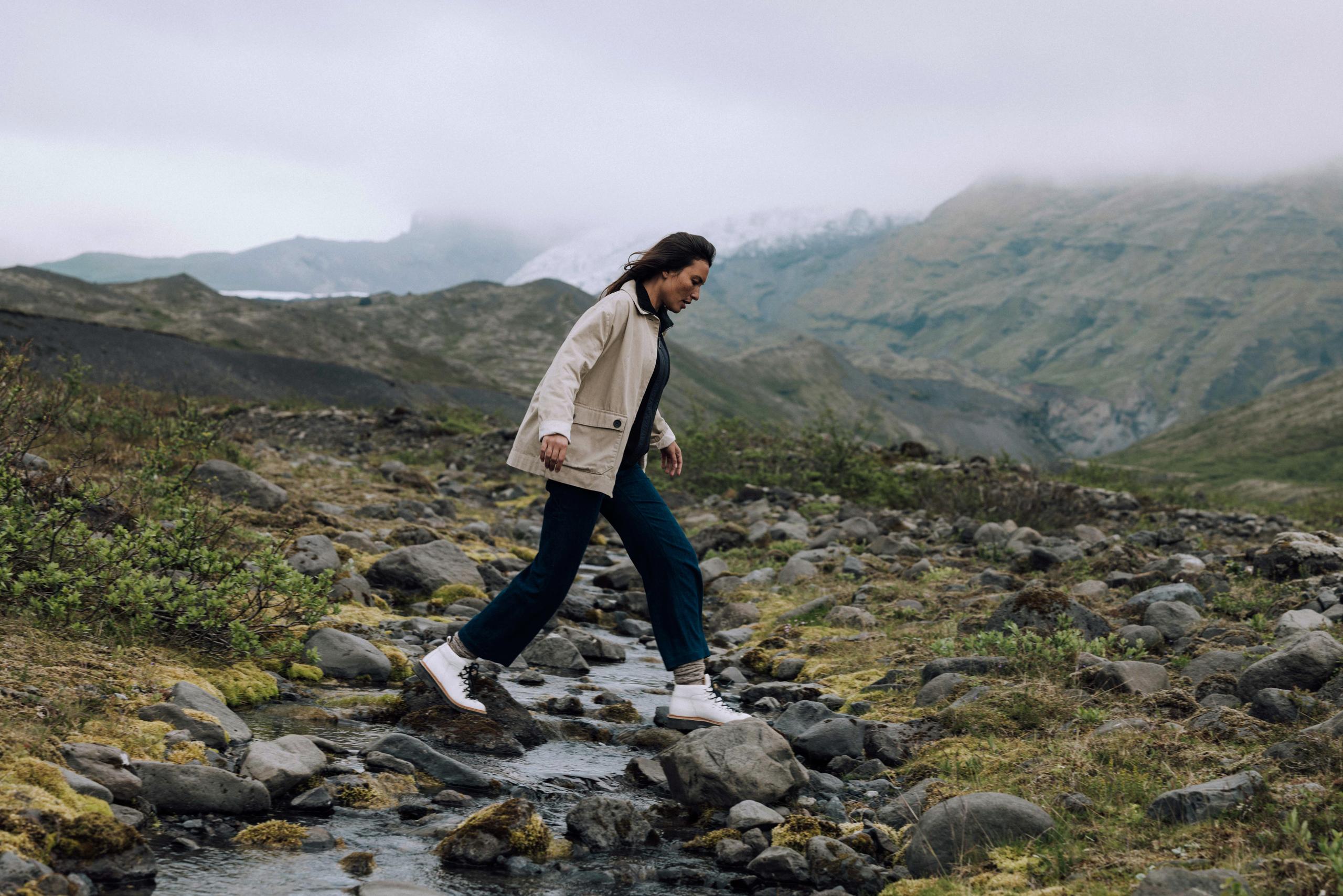 Woman walking across small creek in Iceland landscape