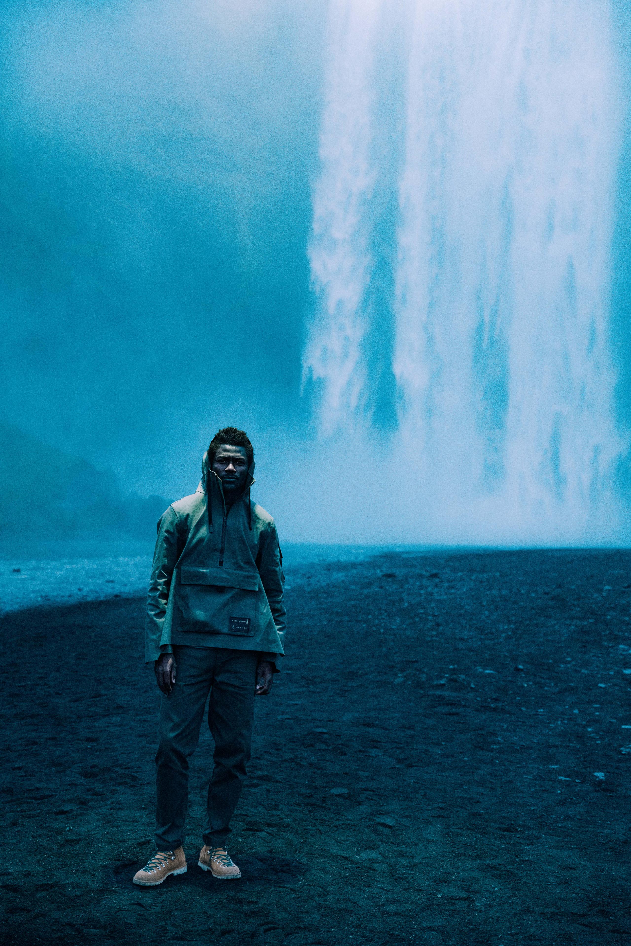 Man in AETHER + Mackintosh Field Anorak in front of waterfall