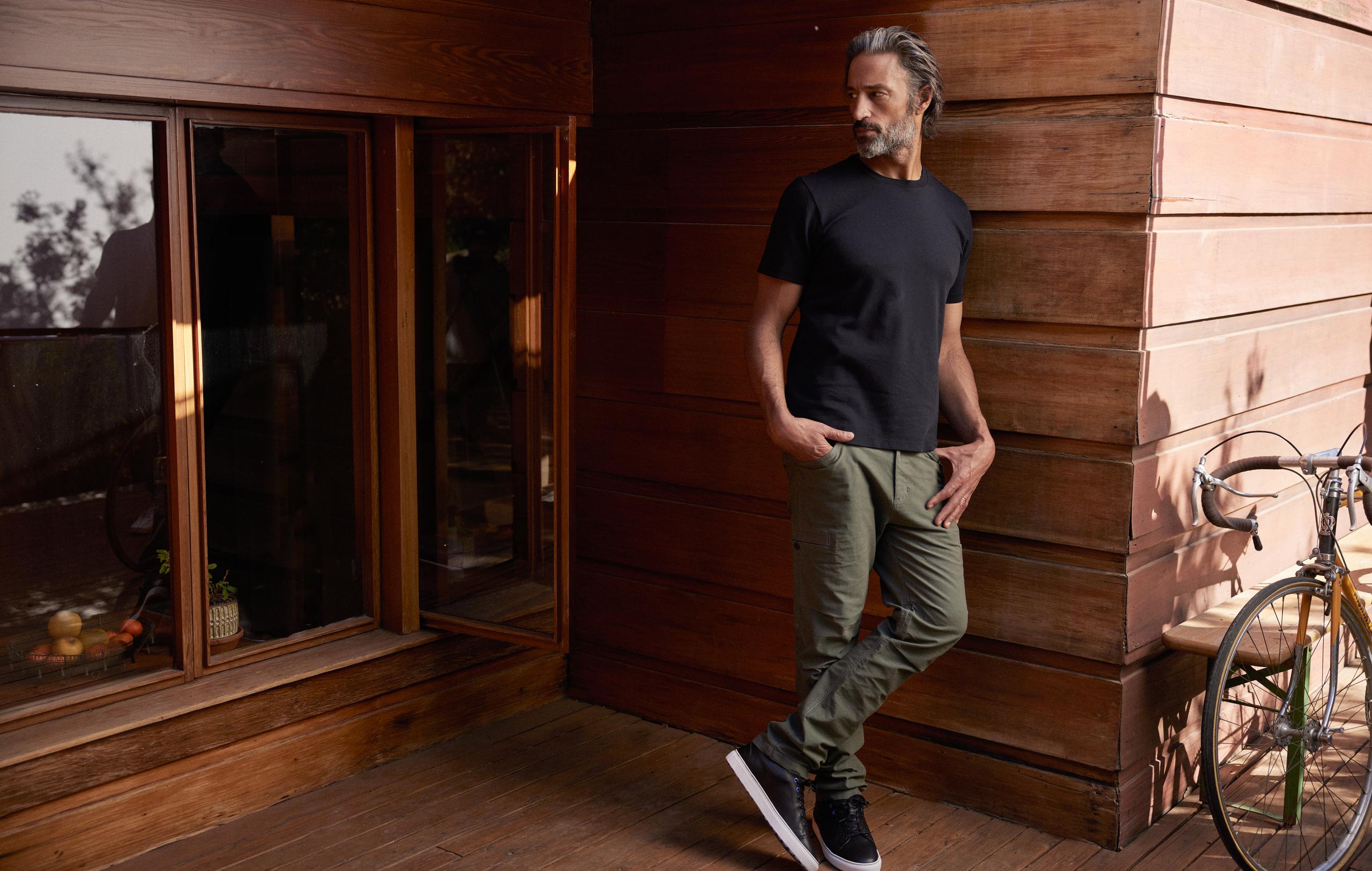 Man wearing Concourse Pant leaning against outdoor wall of mid-century home in California