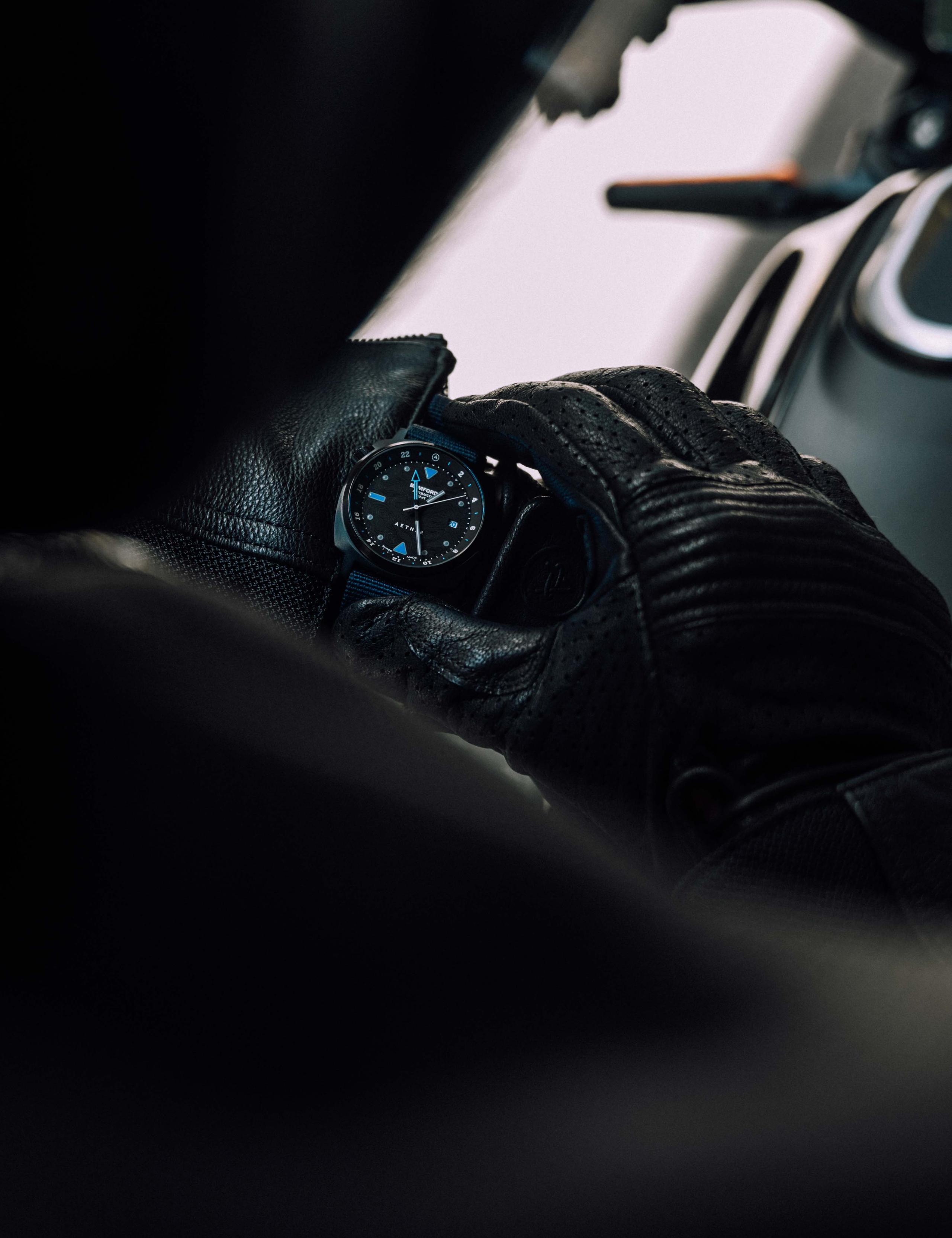 Closeup of motorcyclist looking at AETHER + Bamford GMT watch on his wrist