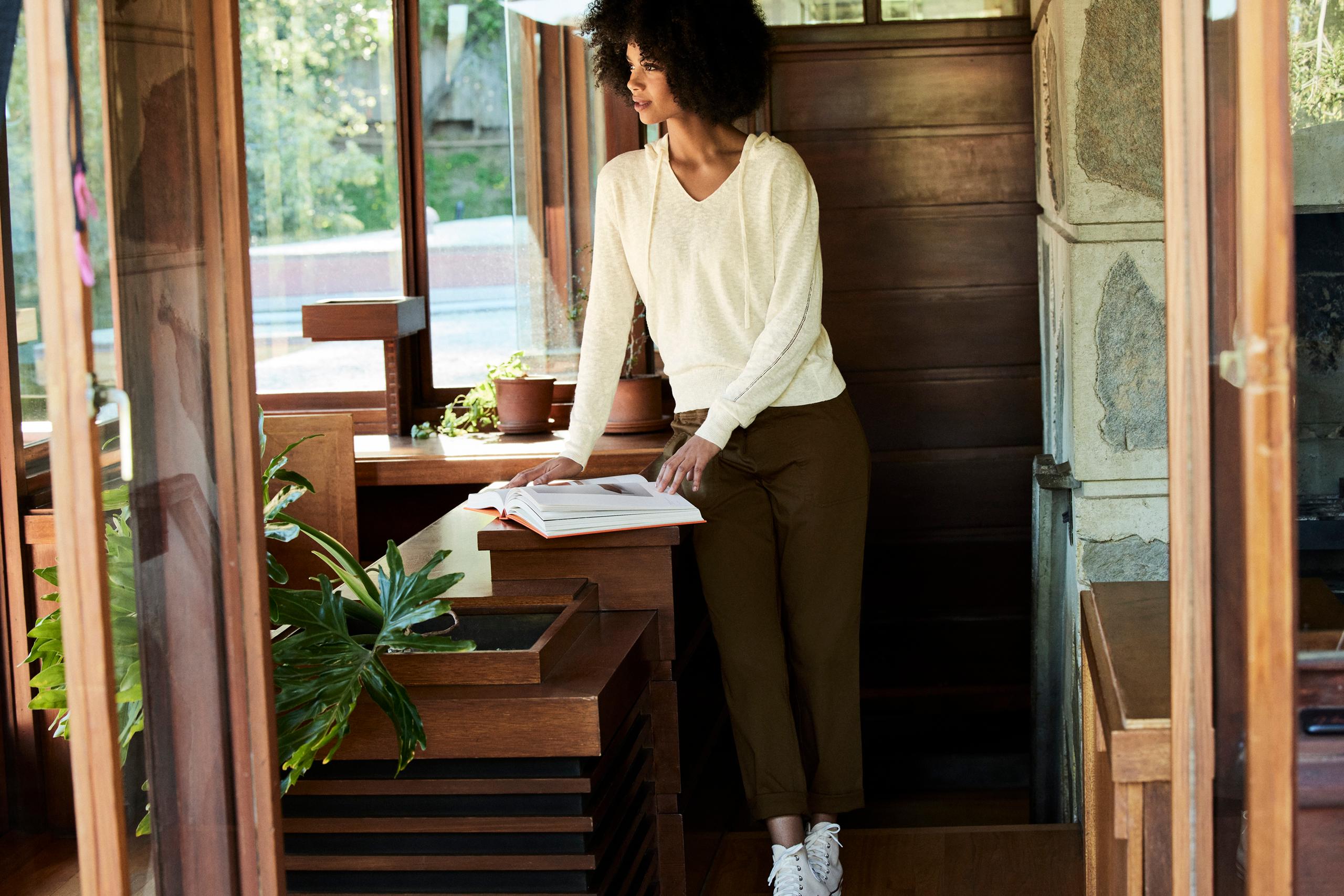 Woman wearing Huston Stretch-Cotton Pant looking at photo book in mid-century home