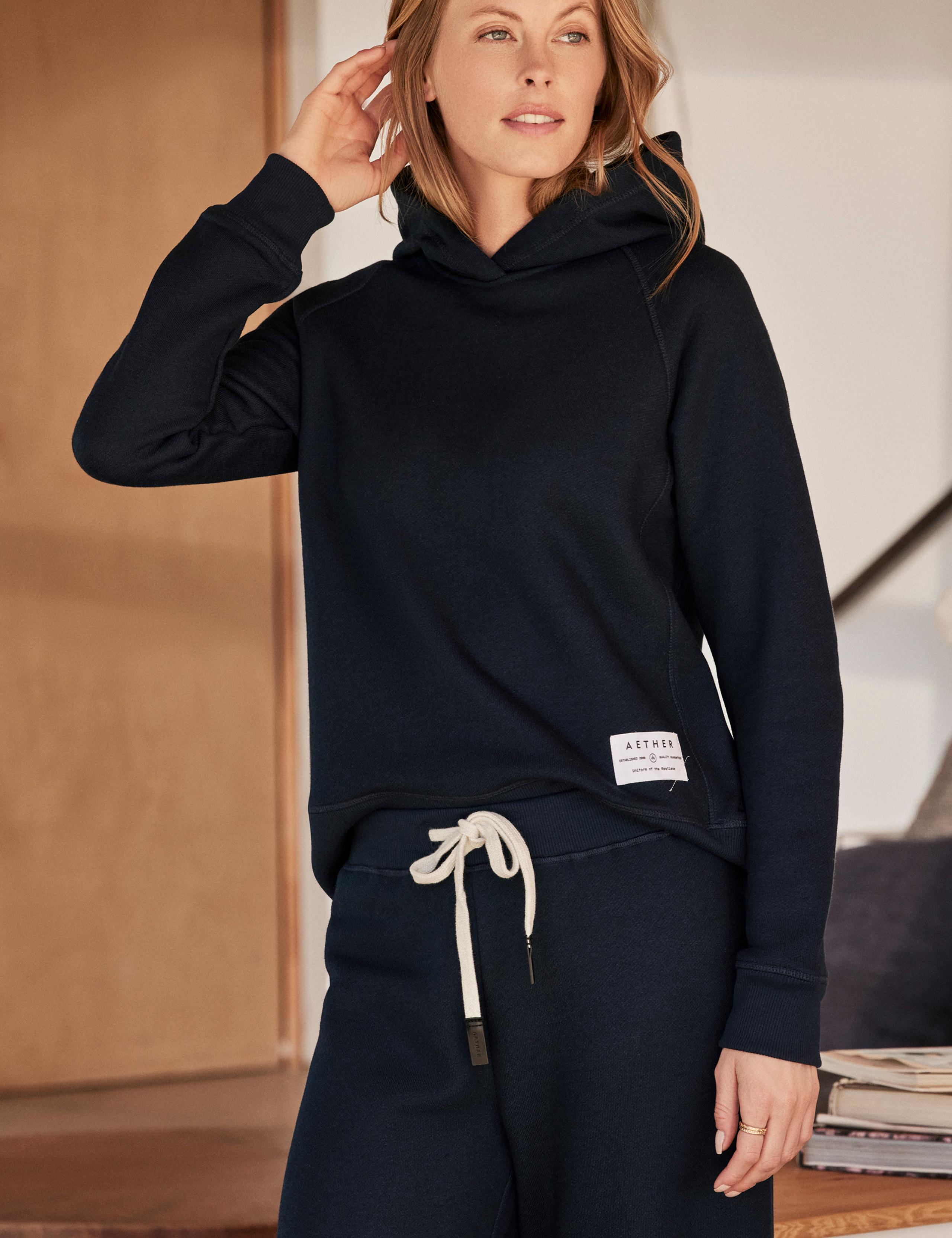 Woman wearing Foundation Hoodie and Foundation Cropped Pant standing in mid-century home