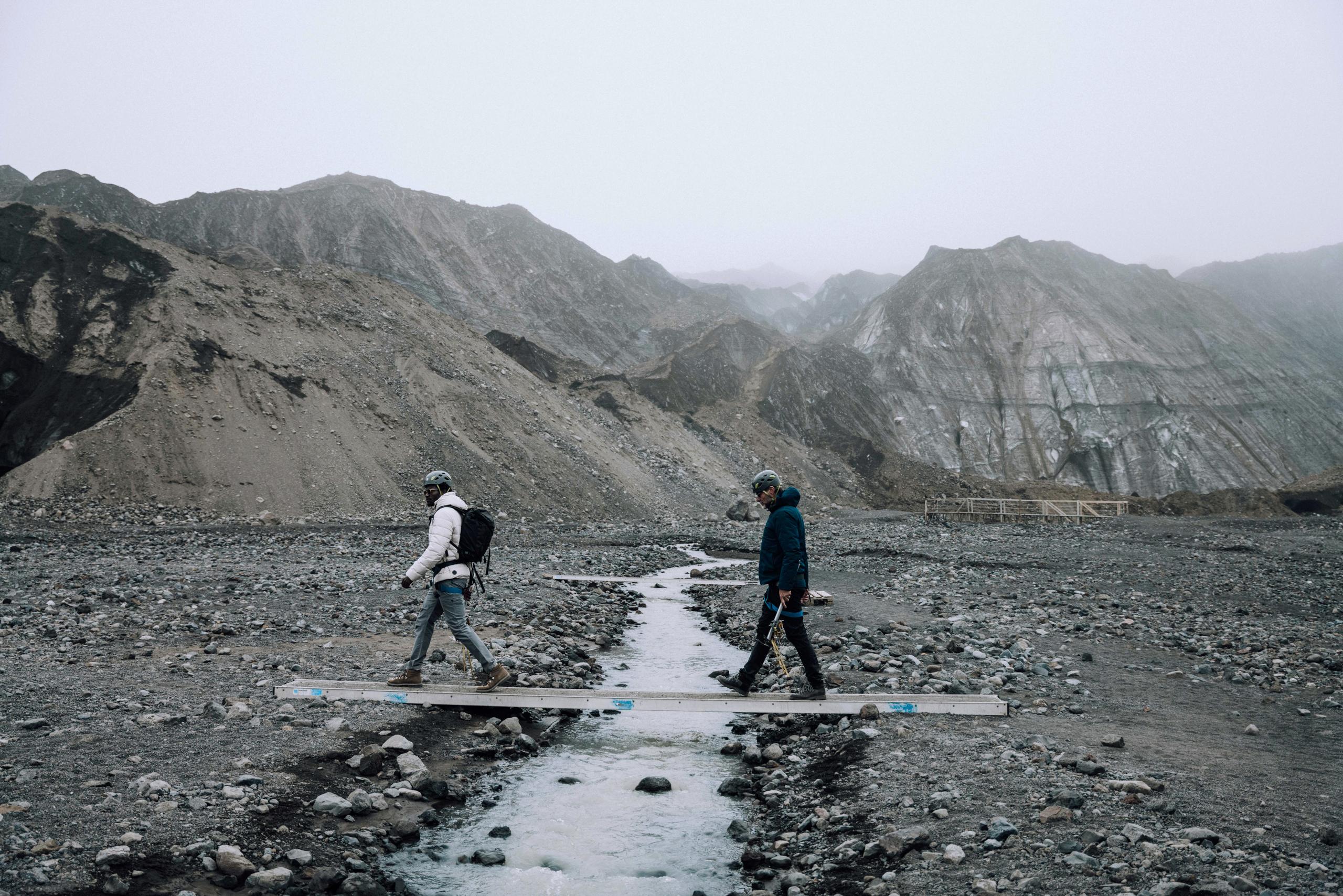 Two men walking across small river in Iceland