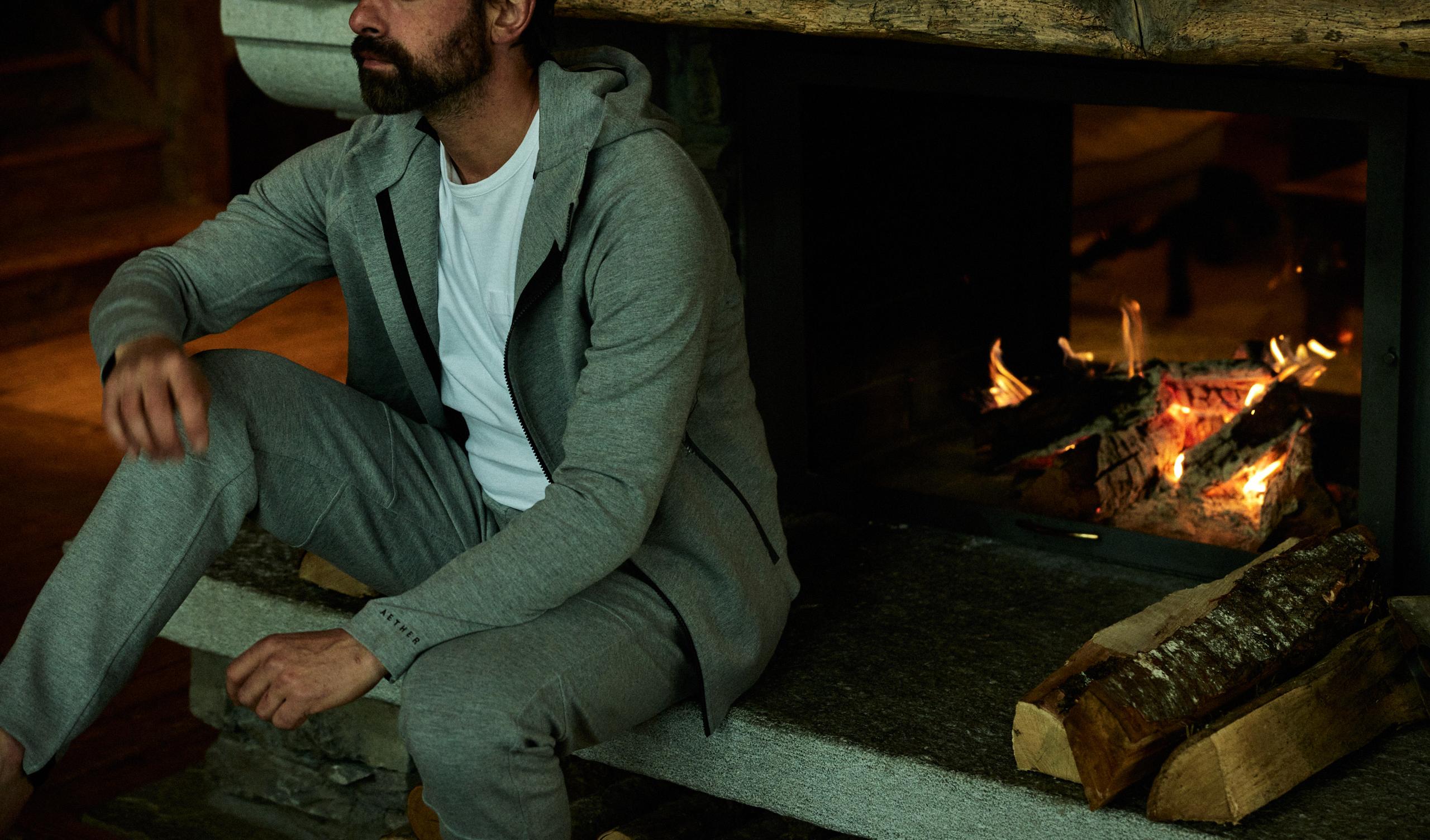 Man wearing Forge Hoodie and Pant in front of fireplace