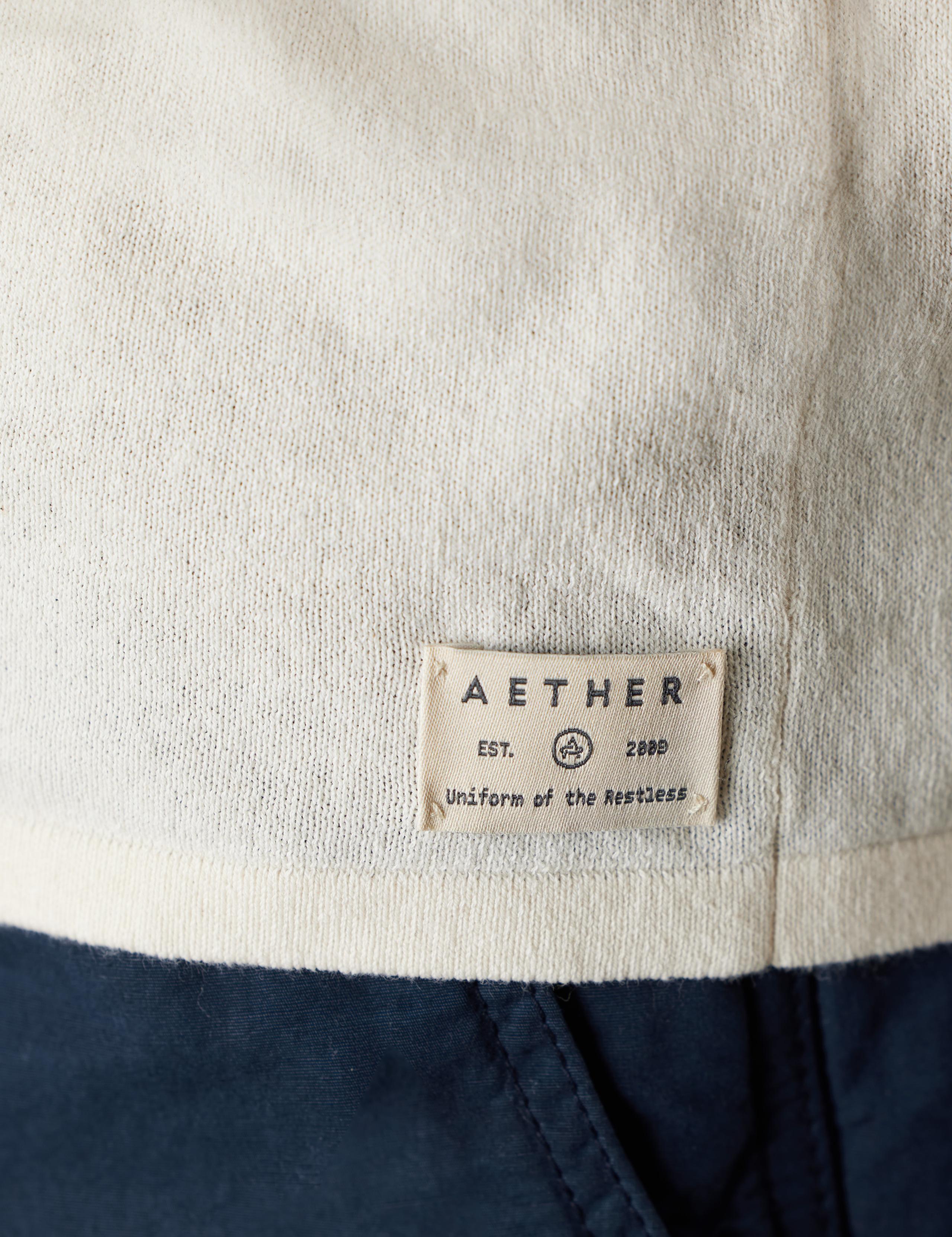 AETHER Label positioned at the hip of the Aero Sweater at the bottom.