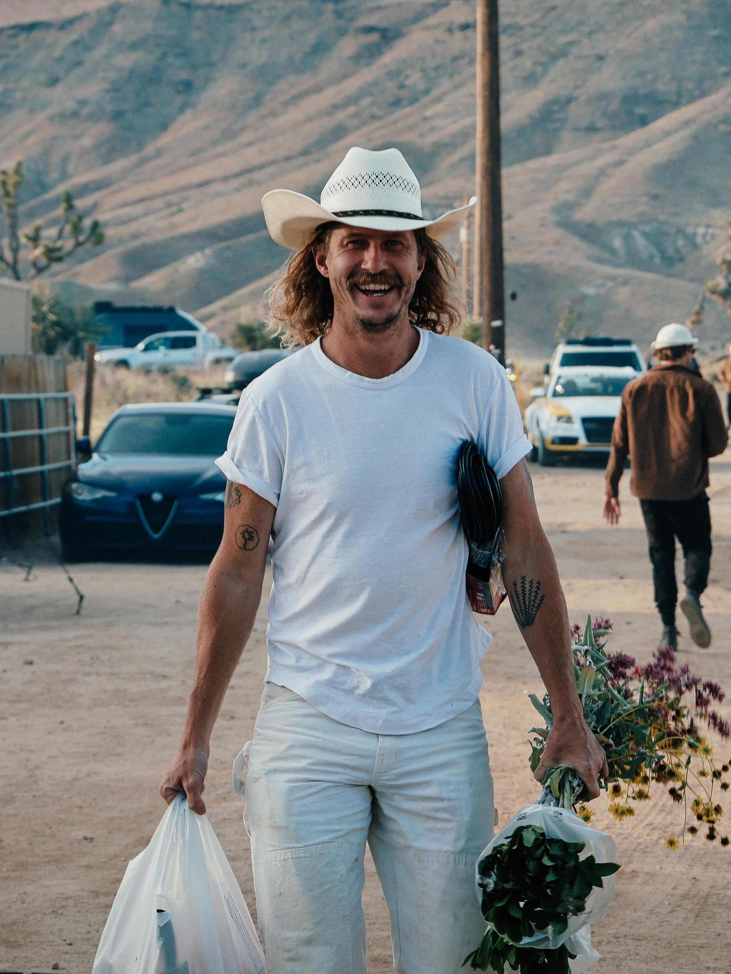 Man in white outfit and white cowboy hat laughing and smiling in Pioneertown