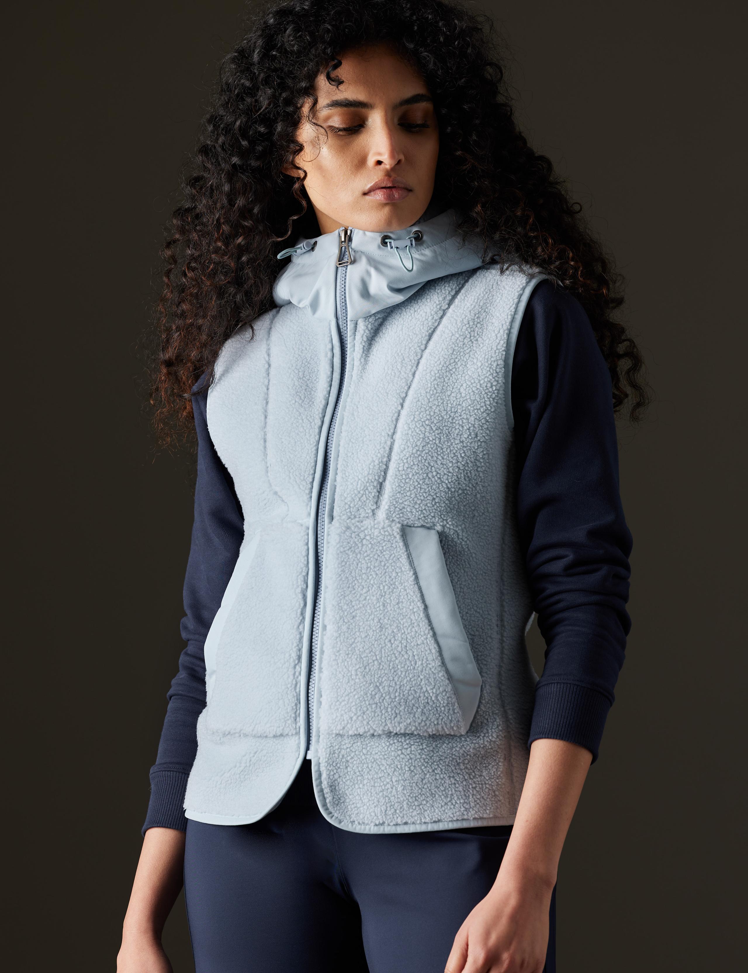 Woman in studio wearing the Terrain Fleece Vest in Flight Blue