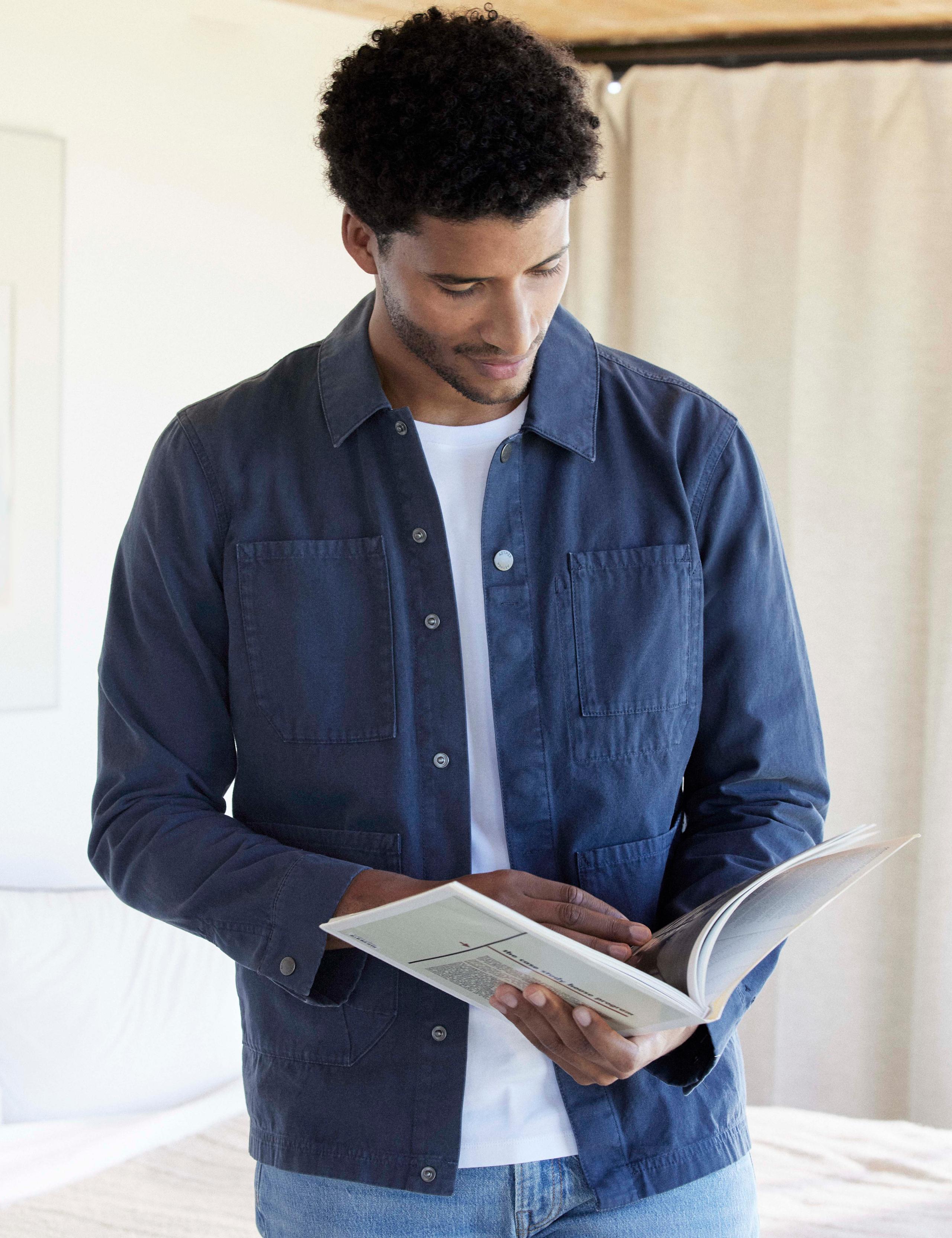 Man wearing Morro Cotton Chore Jacket flipping through pages of photo book in mid-century house