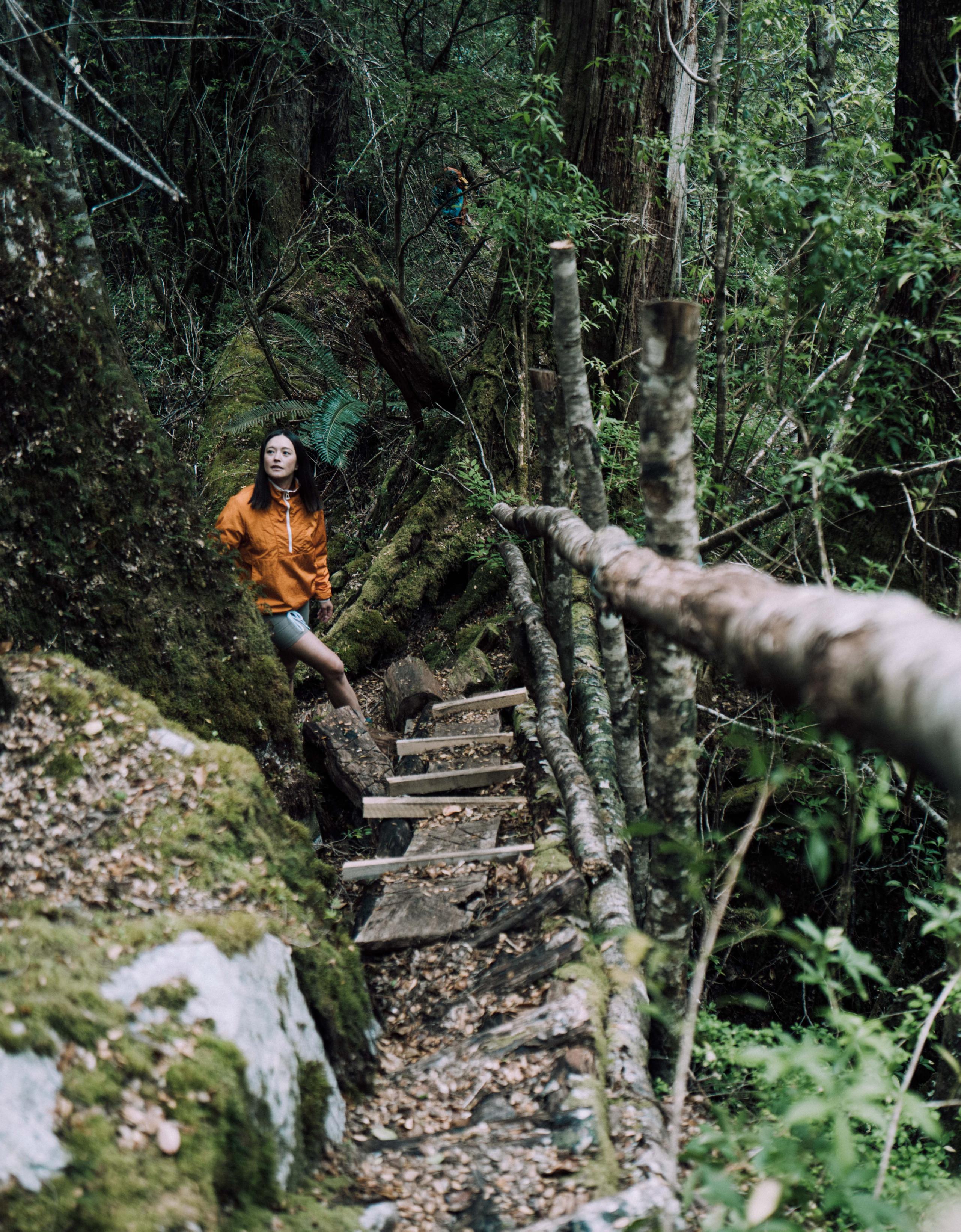 Woman hiking up steep path in forest of Patagonia
