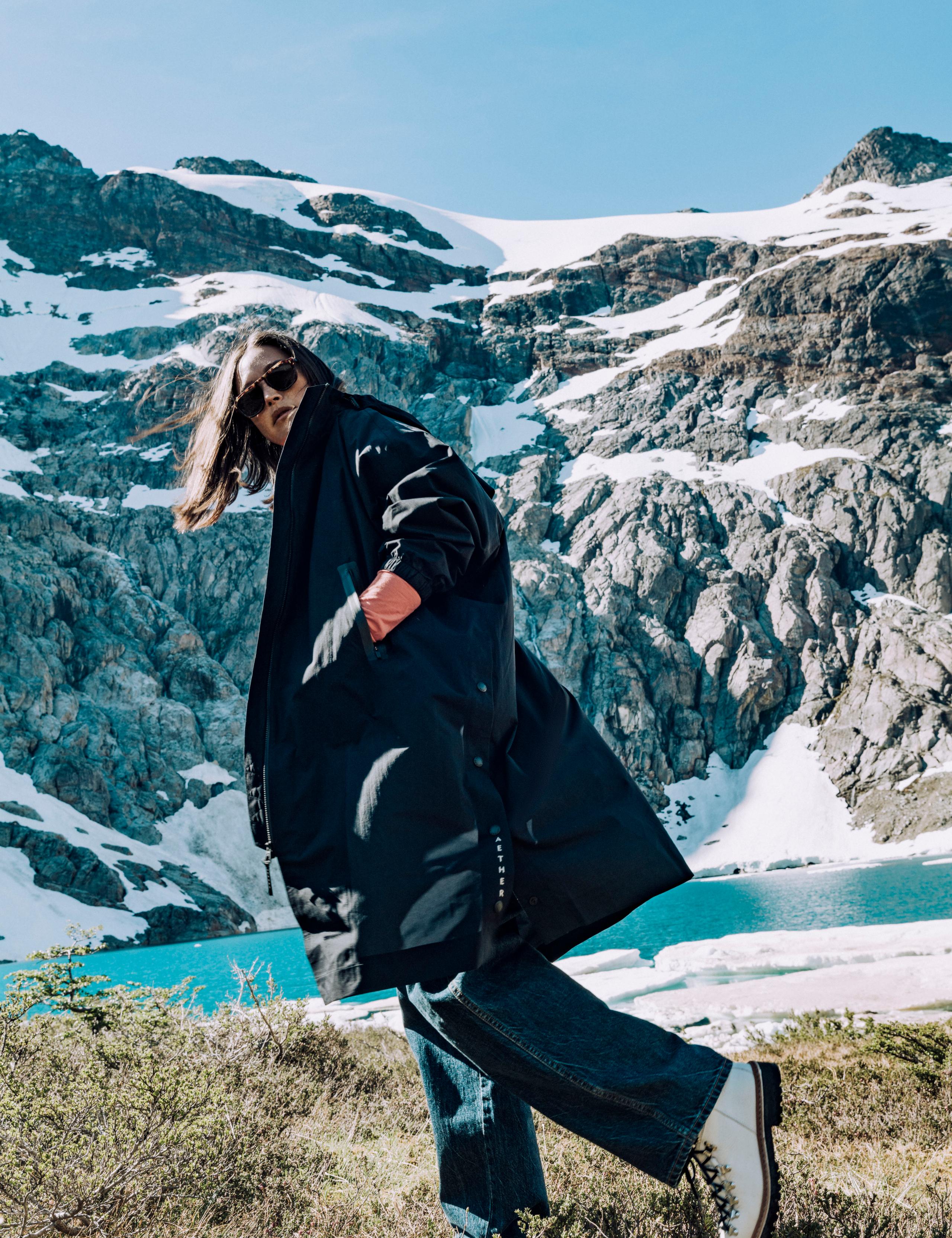 Woman in Kite Packable Rain Poncho walking next to icy lake in Patagonia