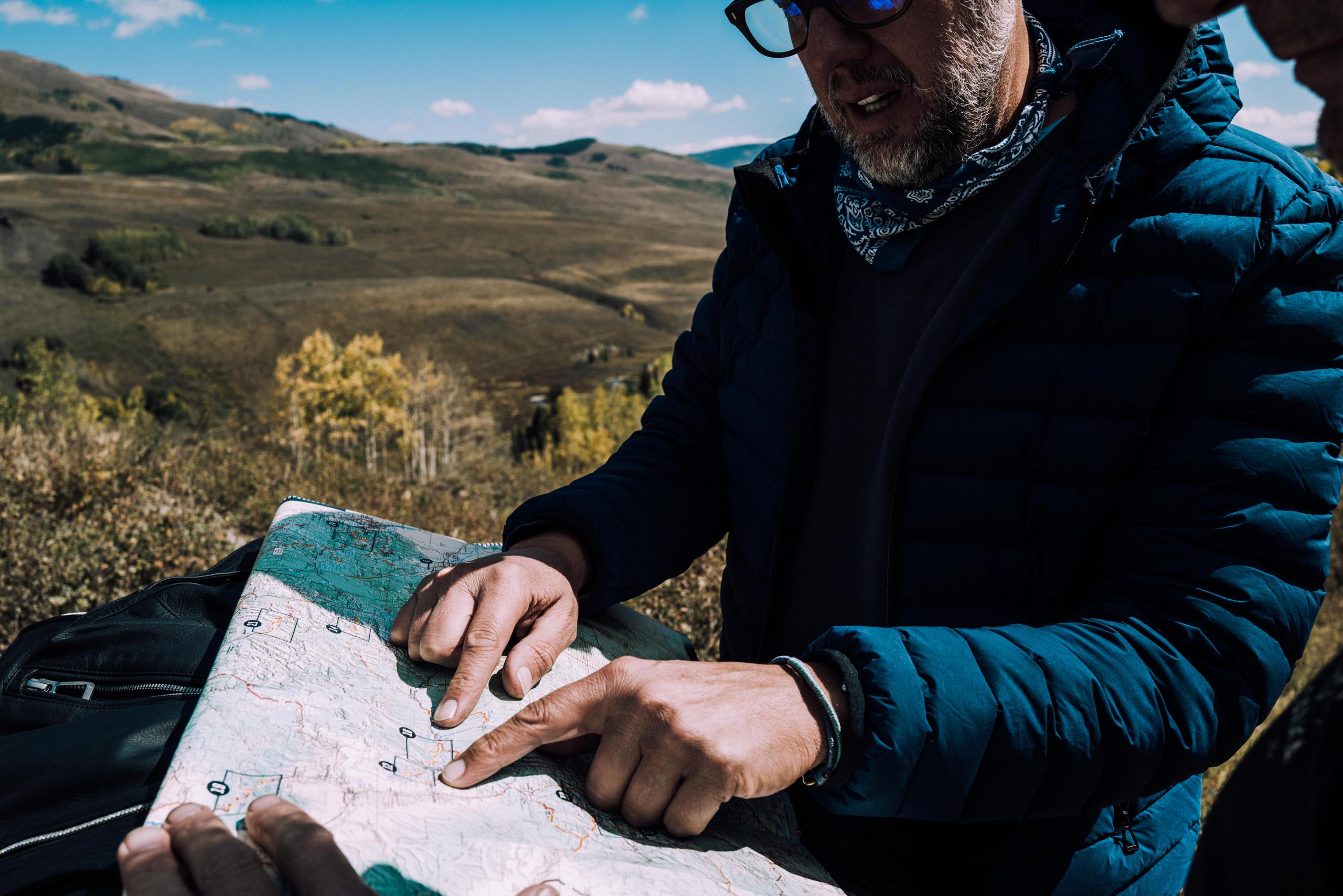 Man pointing to map with Rocky Mountains in background