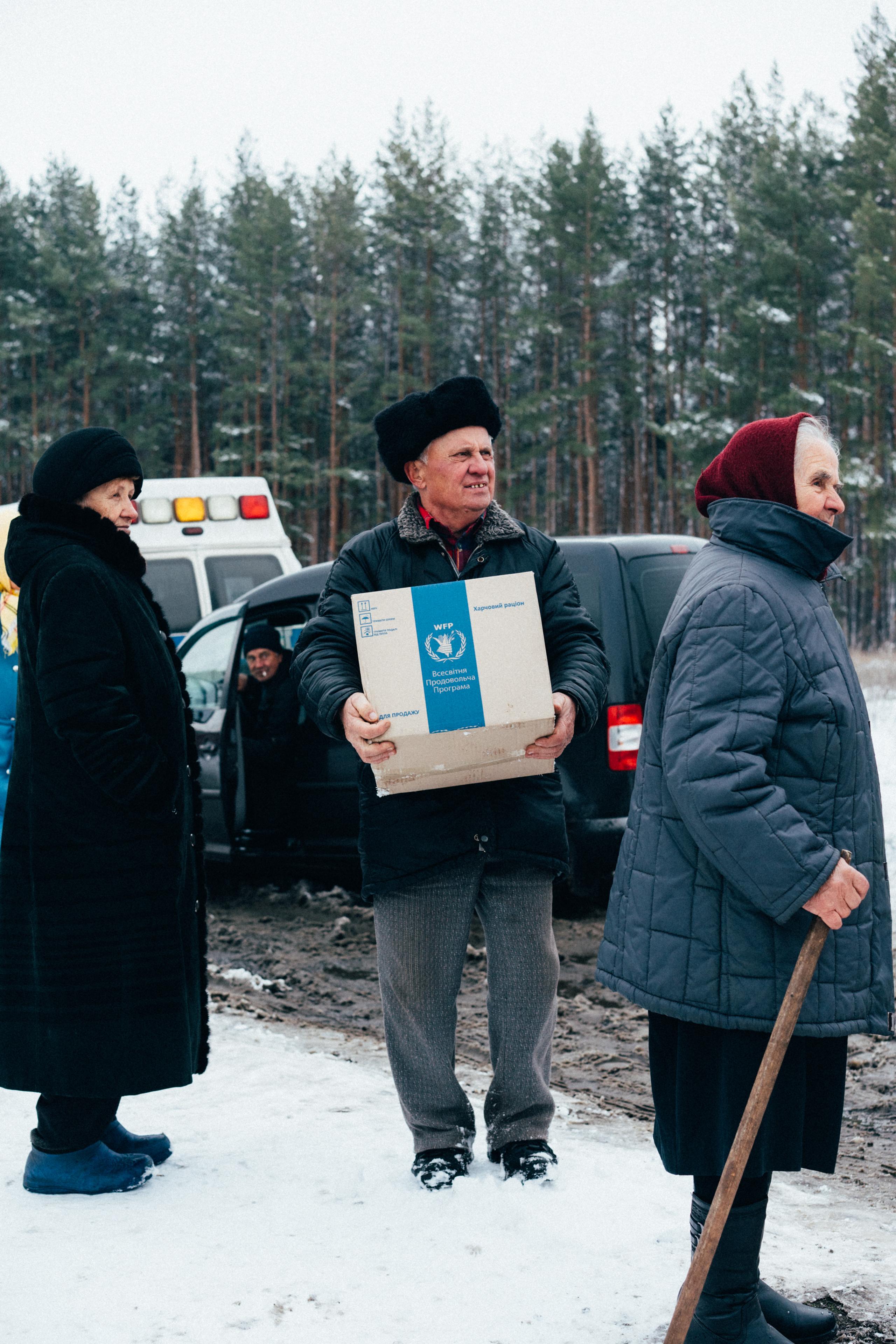 Elderly man holding food ration box