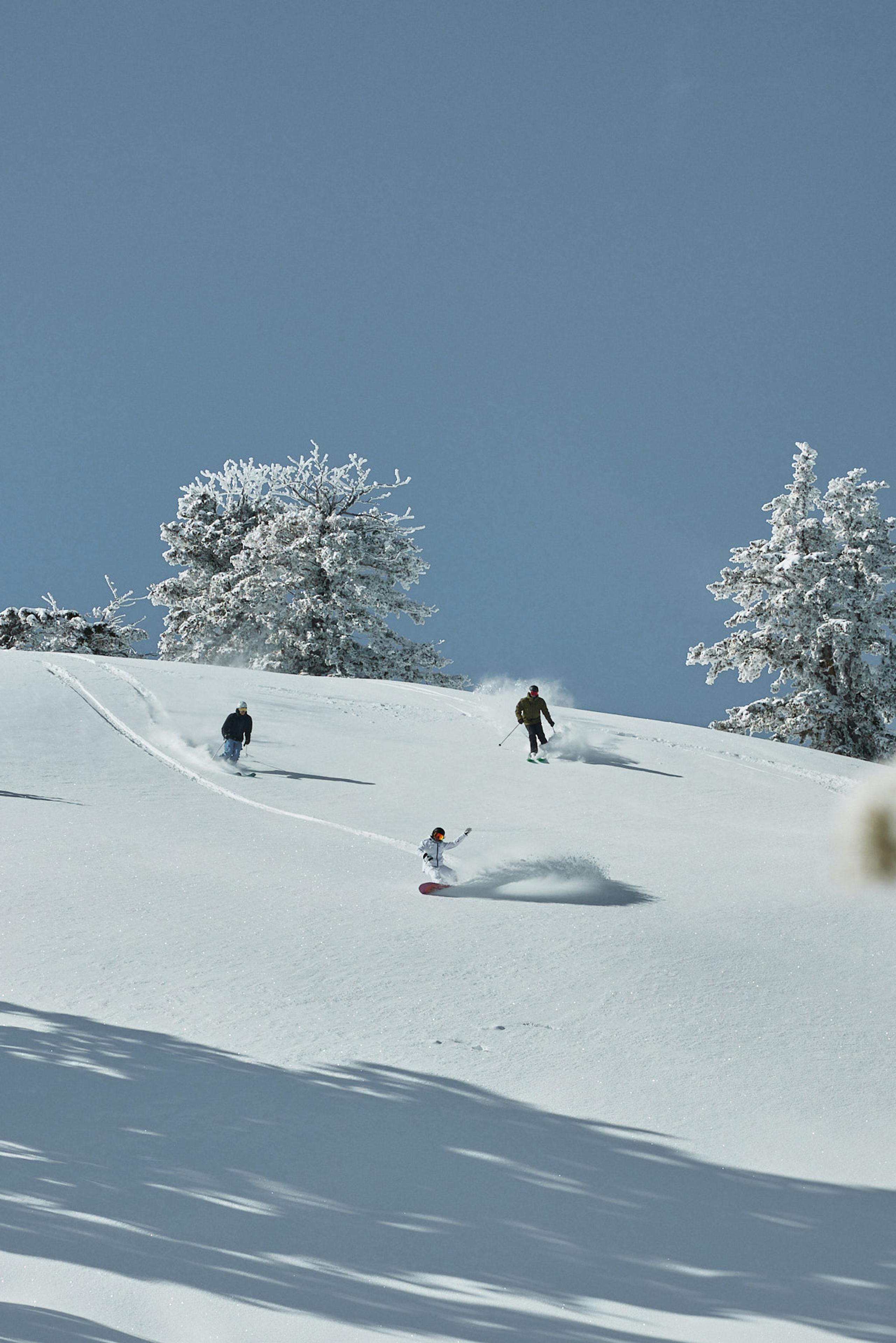 Three people skiing on snowy mountains.