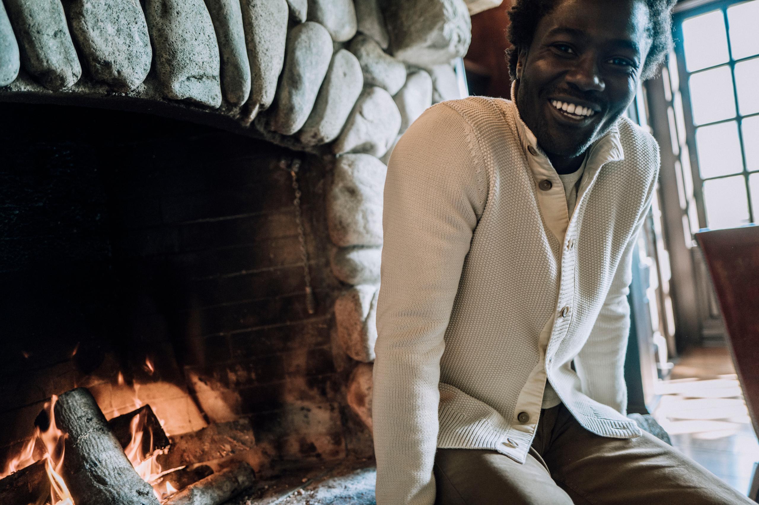 Man in Oliver Button-Up Sweater sitting next to fireplace smiling