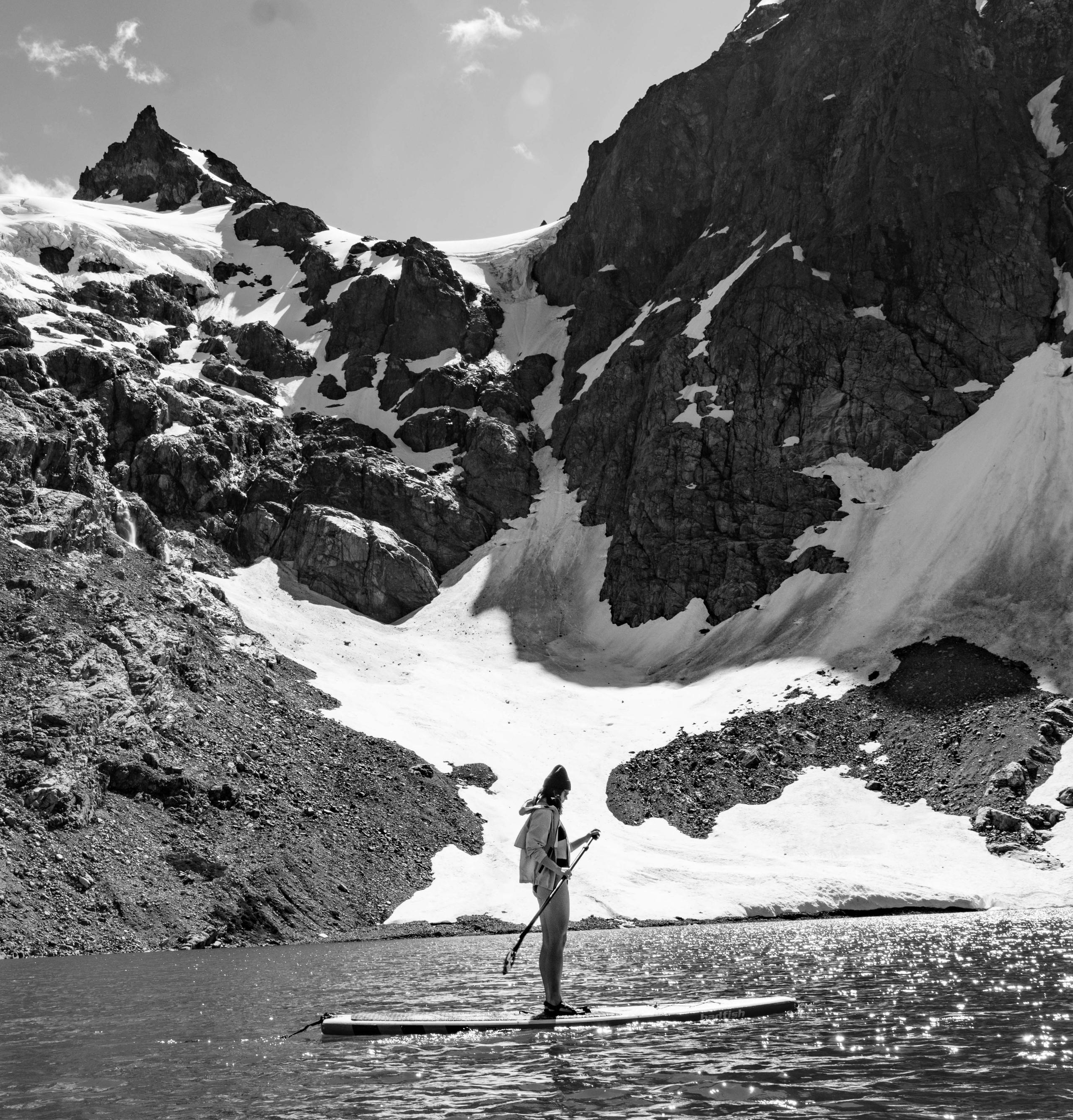 Black and white photo of woman paddle boarding in icy lake in Patagonia