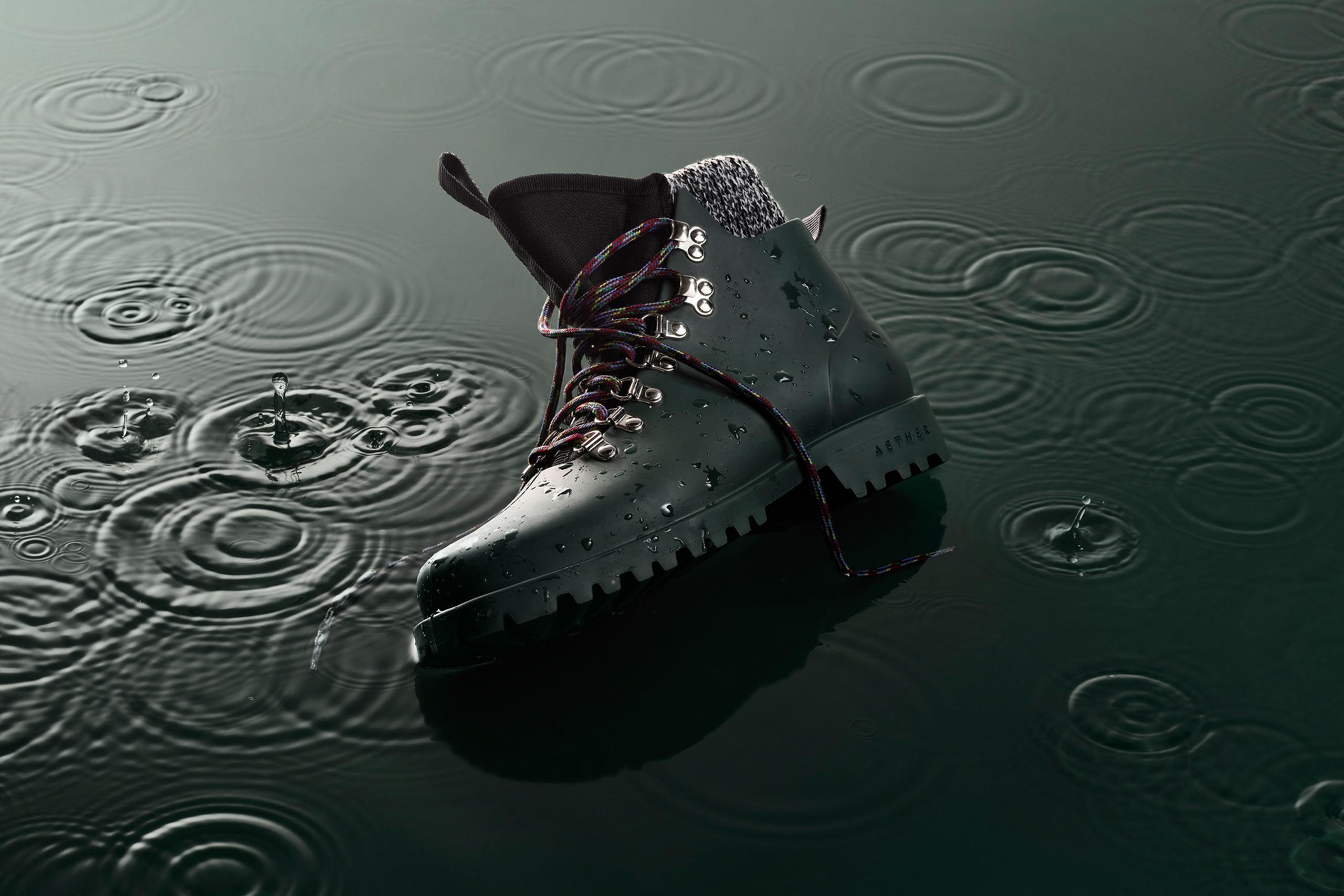 AETHER Rain Boot in shallow water with rain drops falling