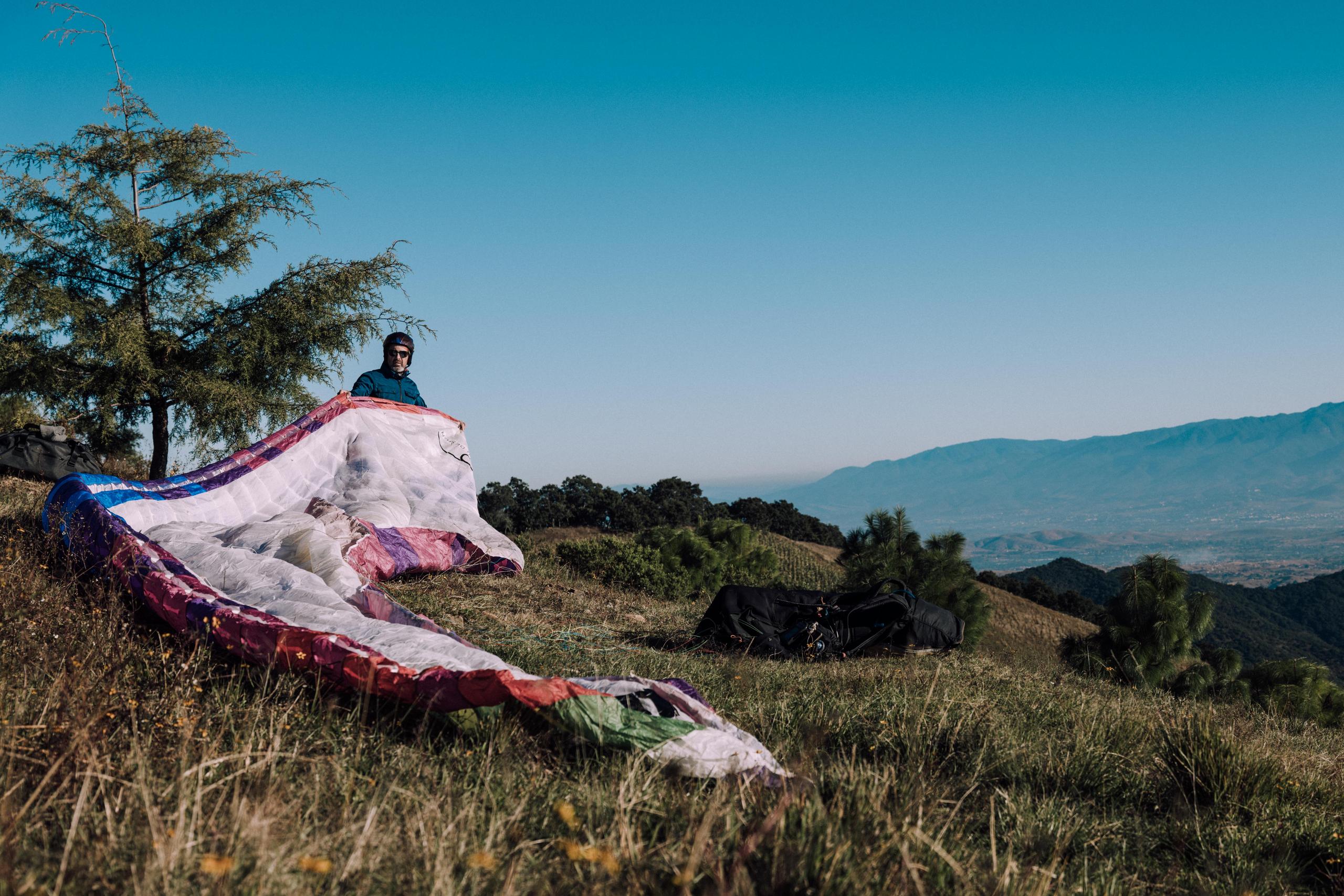 Man unfurling paraglide on mountainside near Oaxaca, Mexico 