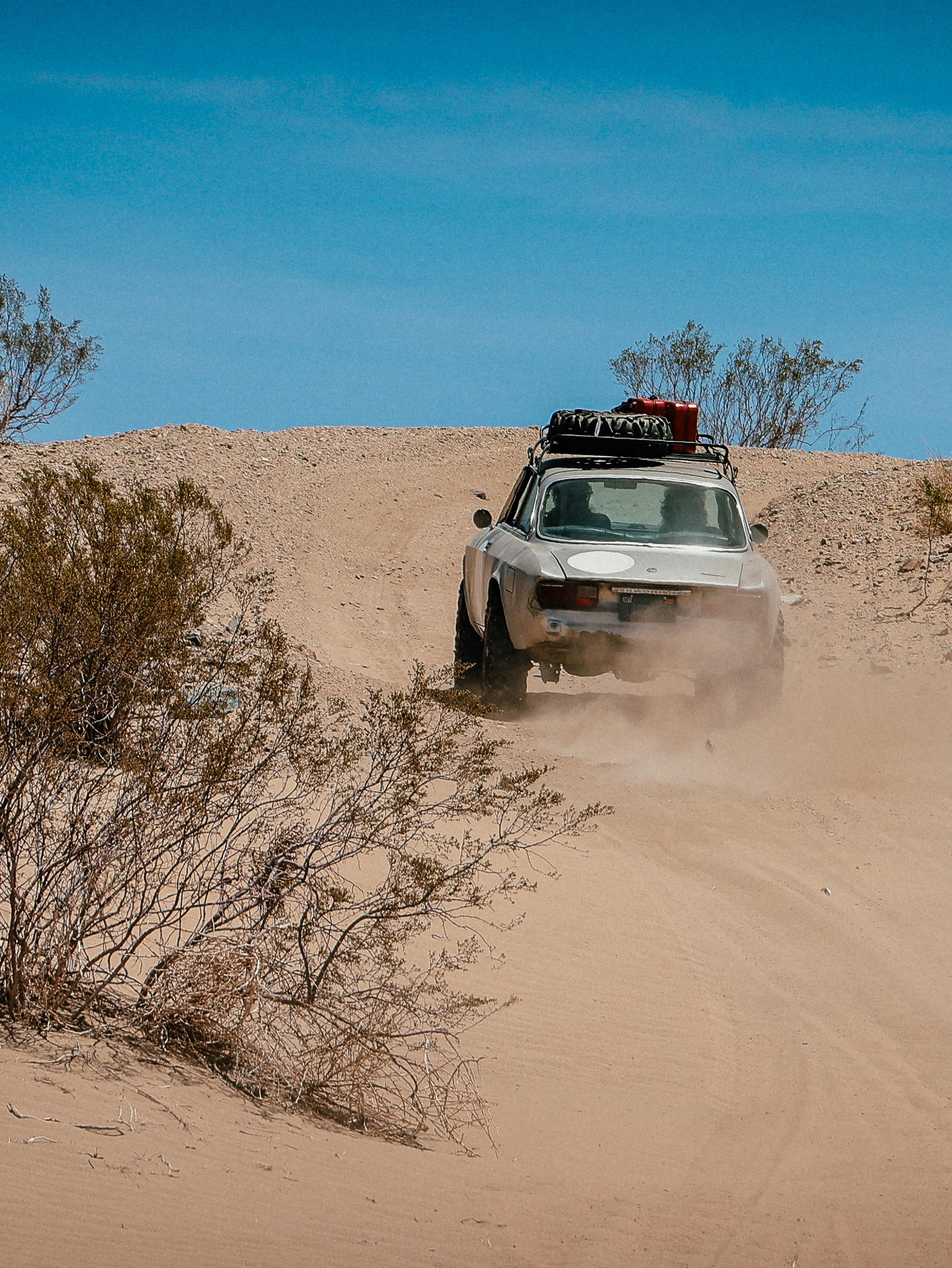 Vintage car driving through desert landscape