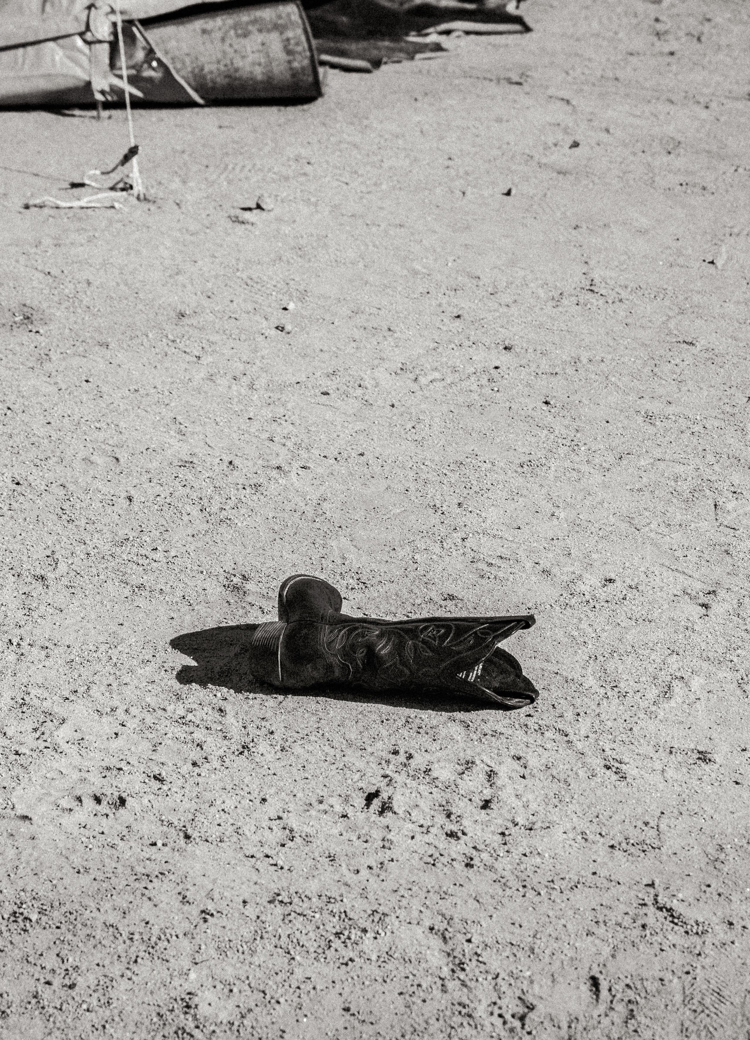 Single cowboy boot laying on dirt ground