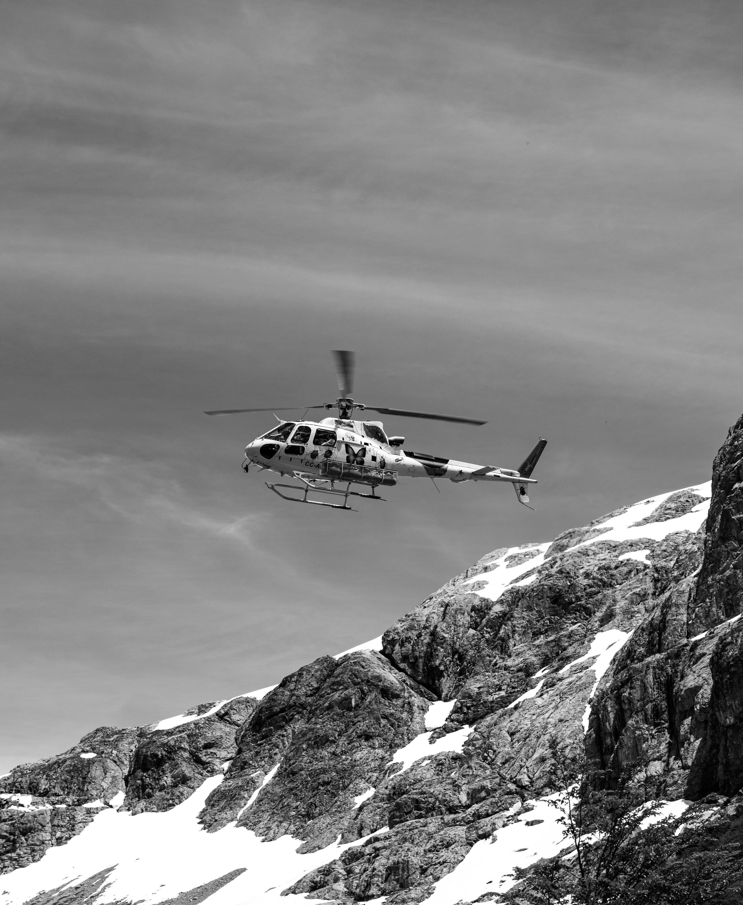 Black and white photo of helicopter near icy mountain range