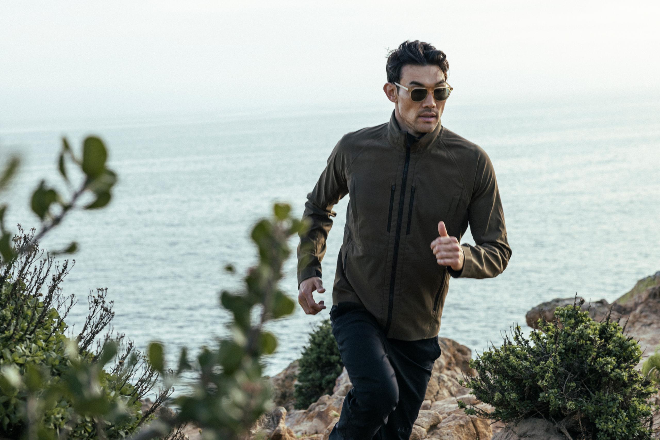 Man running up trail in Malibu hills with Pacific Ocean in the background