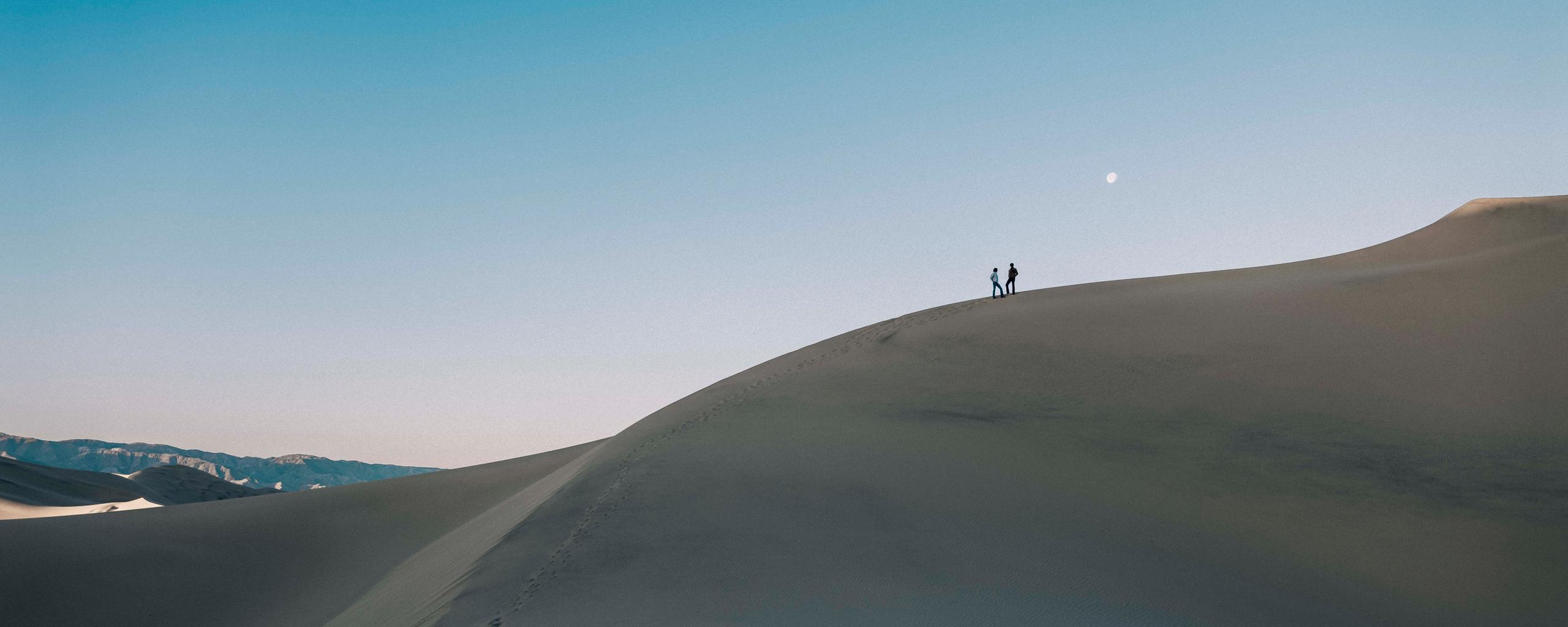 Man and woman standing on sand dune at Imperial Sand Dunes in California