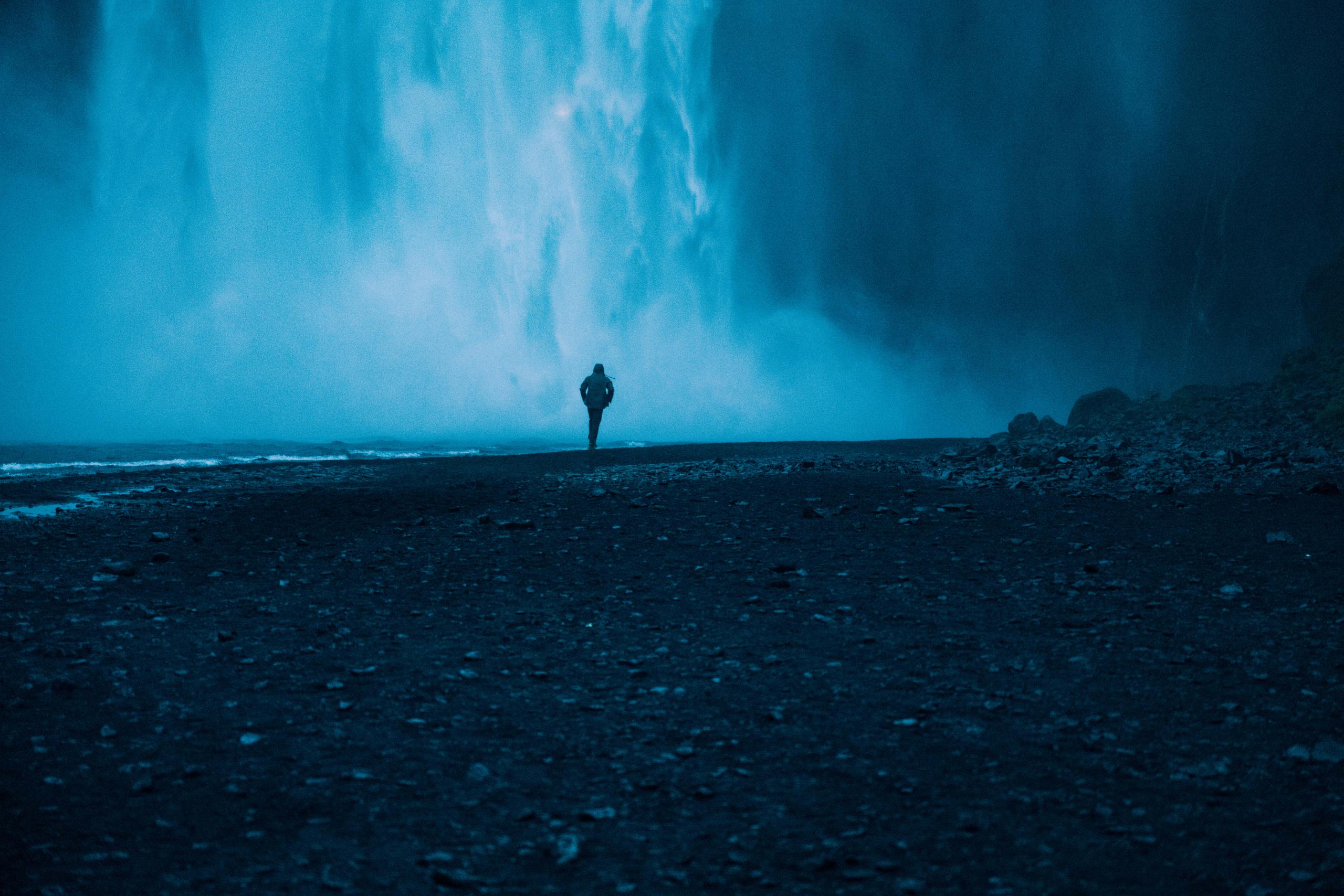 Man walking towards massive waterfall in Iceland