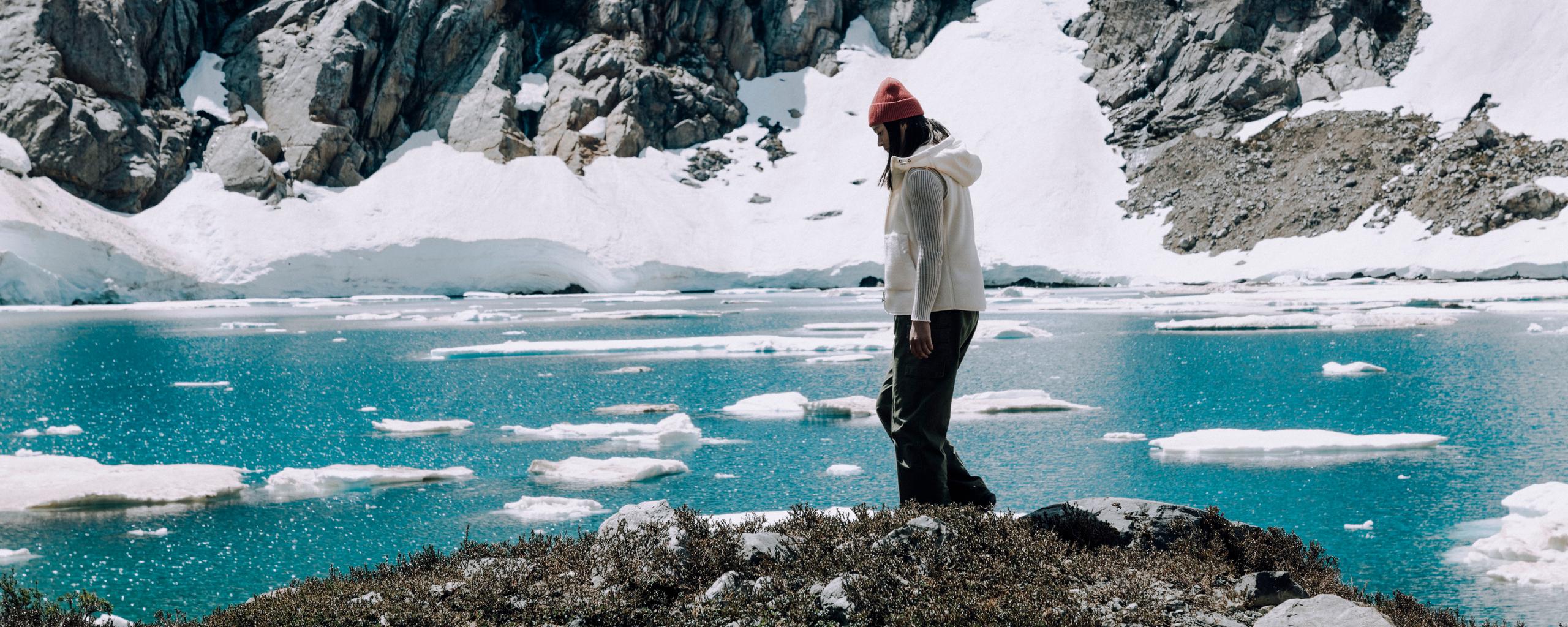 Woman walking along edge of icy lake in Patagonia