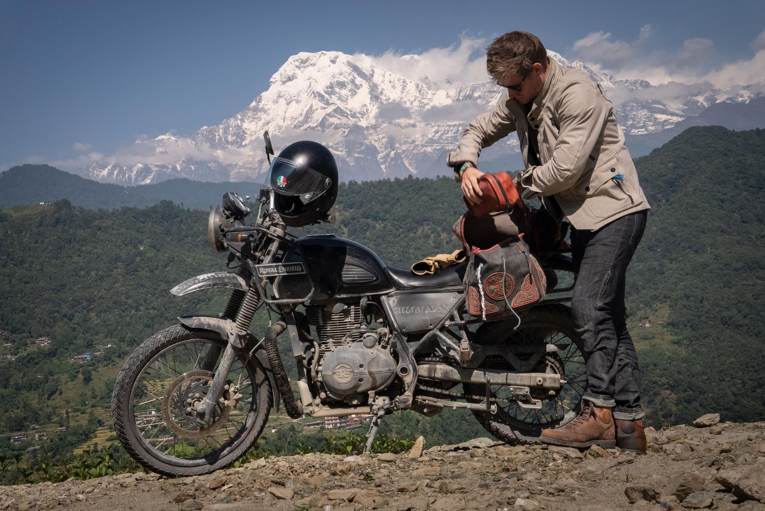 Cory Richards packing back of motorcycle in Nepal landscape