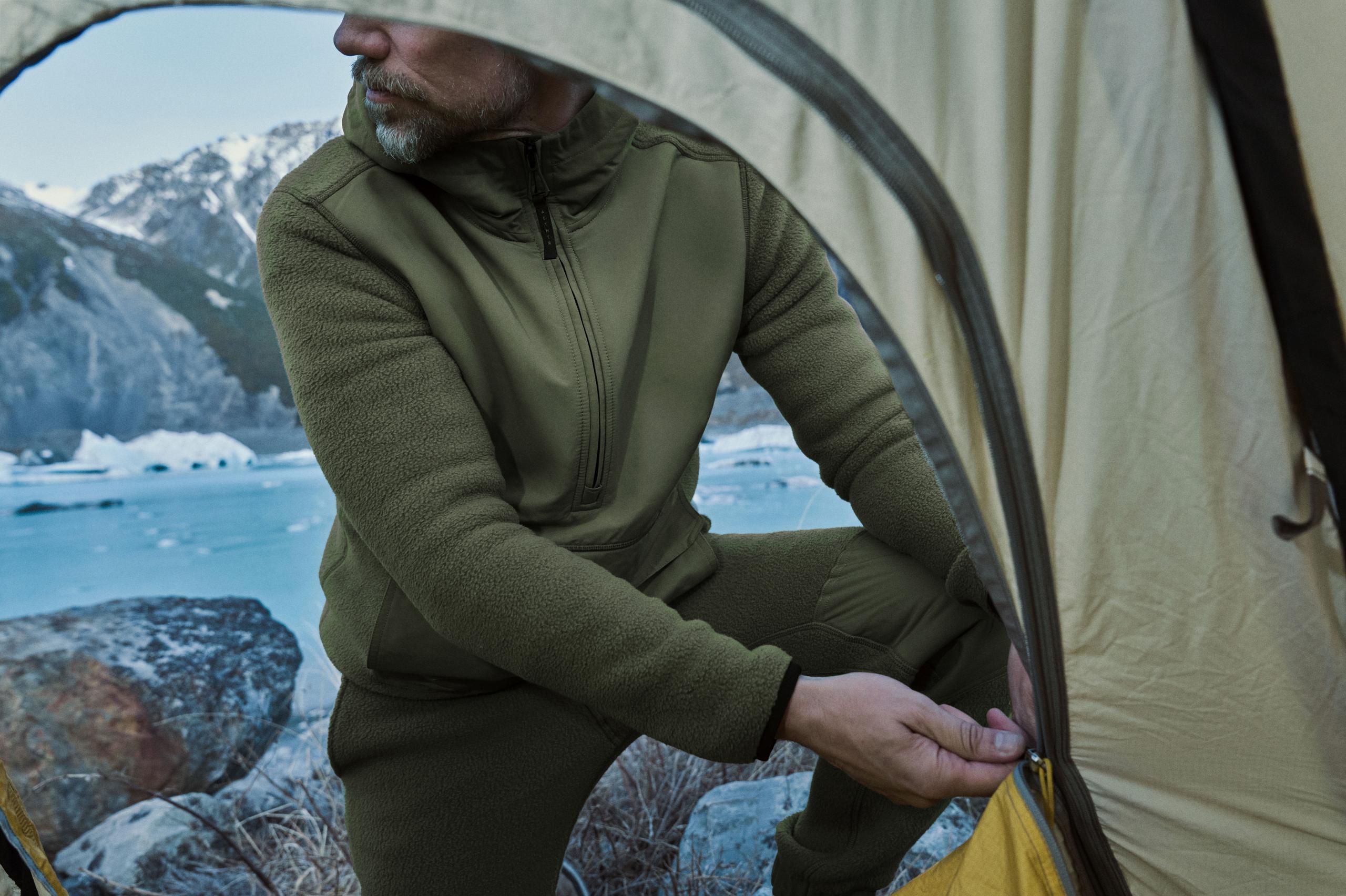 A man zipping up a tent in front of an open tent.