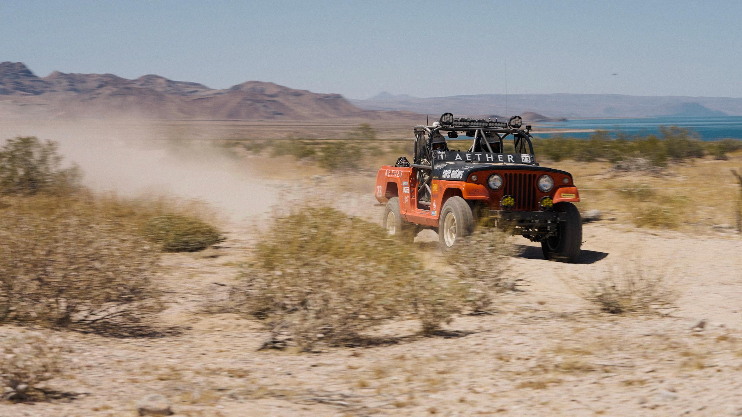 1969 Jeep Commando driving down dirt road in desert landscape