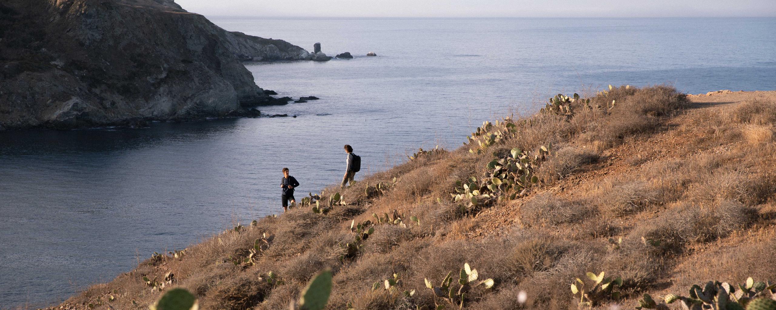 Man and woman hiking down seaside hill off Catalina Island
